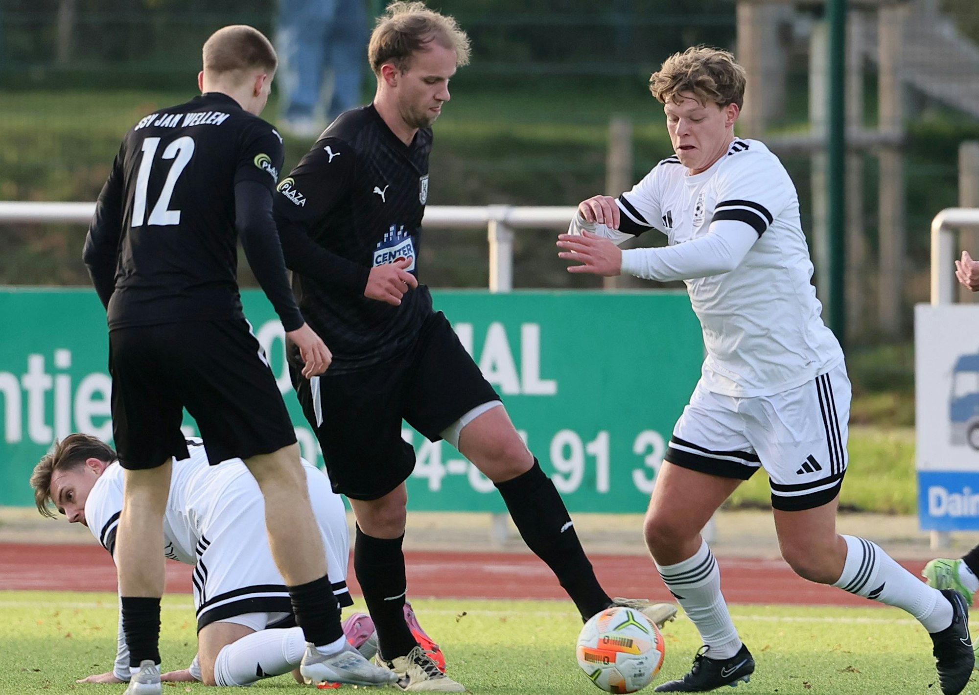 Das Foto zeigt Elsdorfs Niklas Kühnapfel (r.), der sich mit Ball der Übermacht zweier Wellemer Gegenspieler stellt.