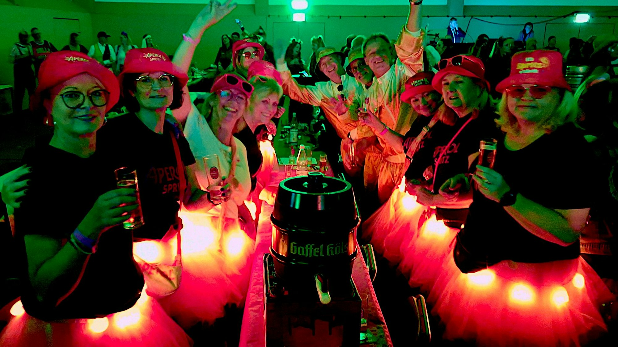 Frauen in Kostümen mit beleuchteten Röckchen feiern an einem Tisch.