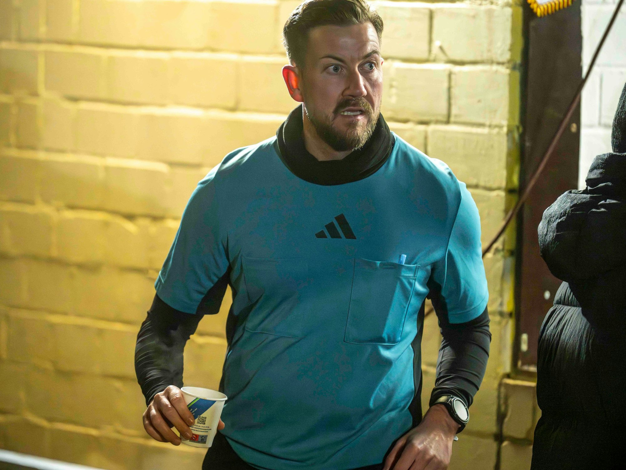 Schiedsrichter-Assistent Ron Fuß hält in der Halbzeitpause ein Heißgetränk in der Hand.