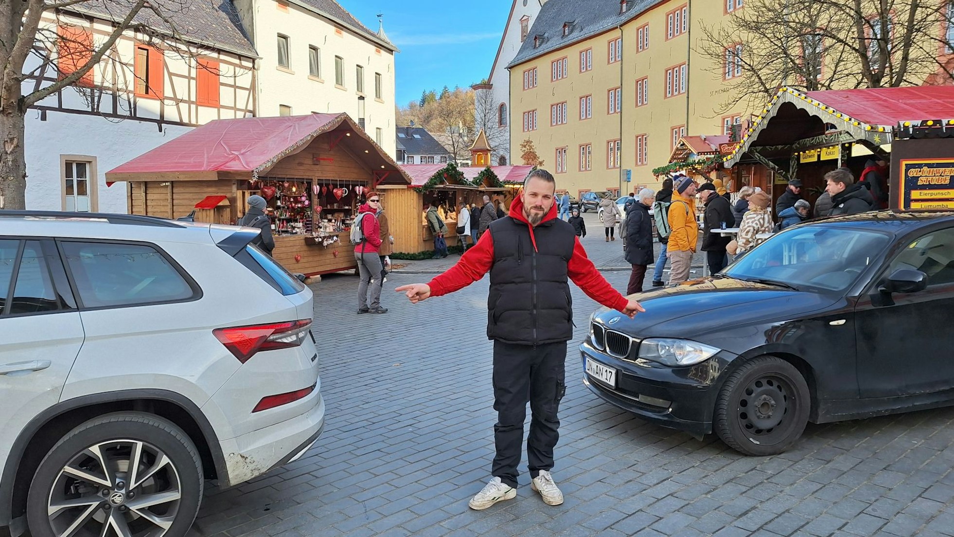 Der Vorsitzende des Stadtmarketingvereins zeigt auf die schmale Lücke zwischen den beiden geparkten Autos, die die Zufahrt versperren.