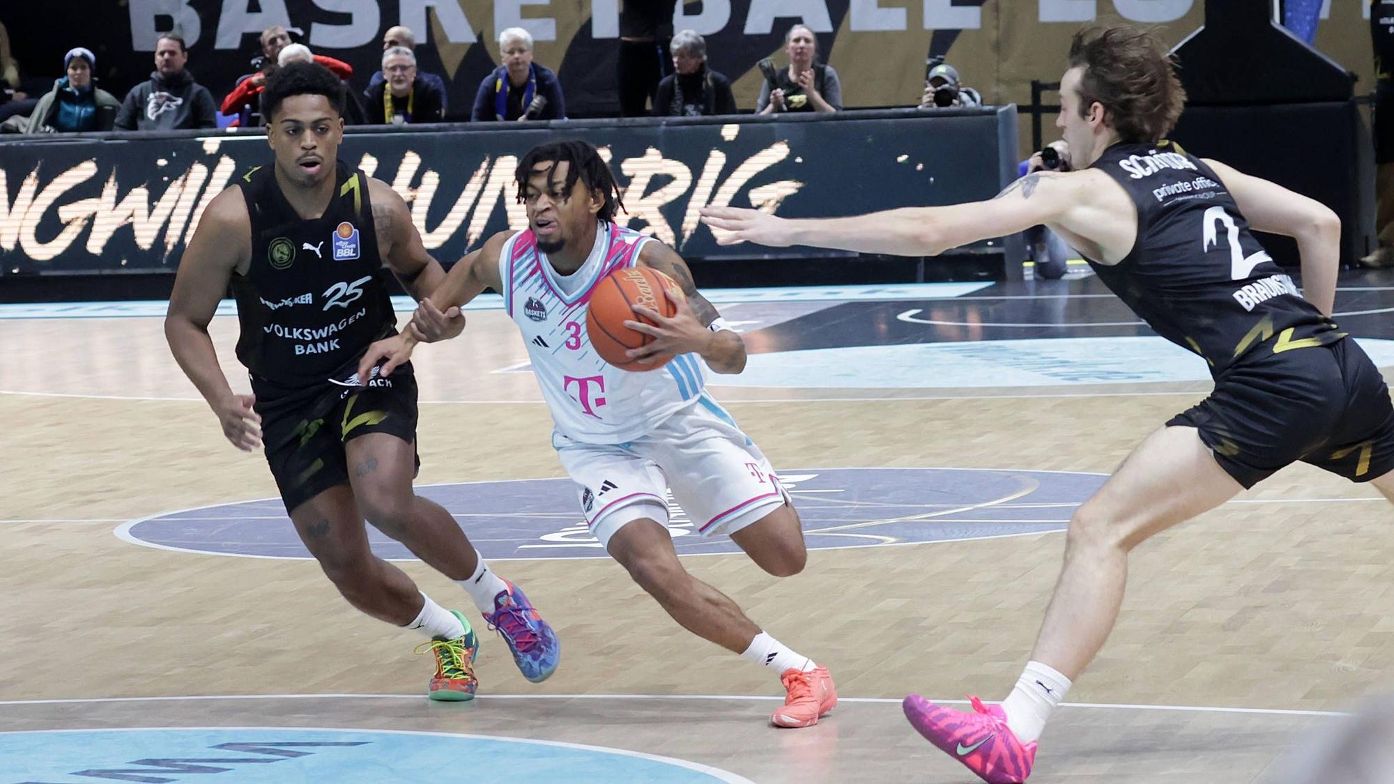 Bonns Aufbauspieler Zach Cooks zieht gegen die Braunschweiger Grant Sherfield (links) und Benny Schröder (rechts) zum Korb.