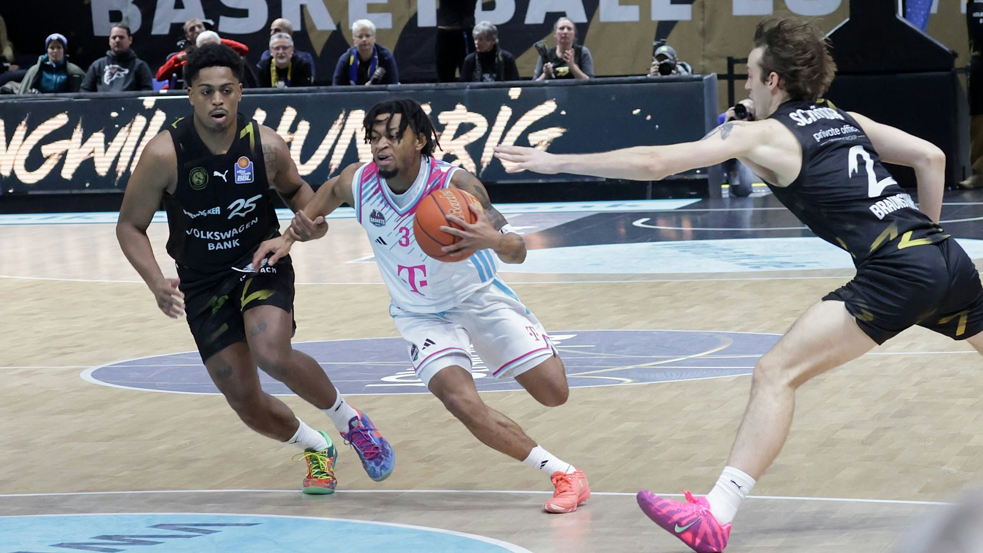 Bonns Aufbauspieler Zach Cooks zieht gegen die Braunschweiger Grant Sherfield (links) und Benny Schröder (rechts) zum Korb.