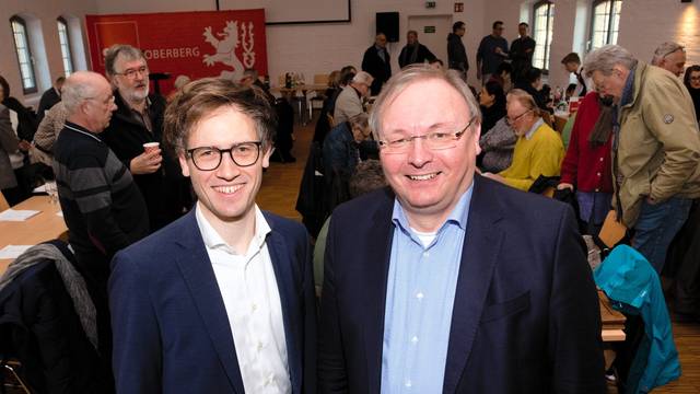 Zwei Männer stehen im Anzug nebeneinander.