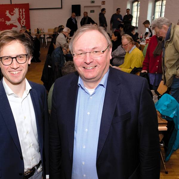 Zwei Männer stehen im Anzug nebeneinander.