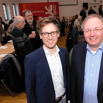 Zwei Männer stehen im Anzug nebeneinander.