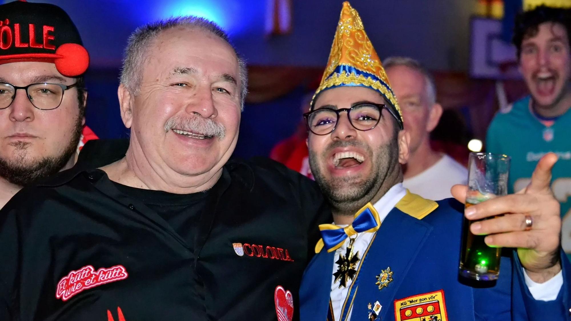 Zwei Jecken liegen sich in den Armen und feiern.