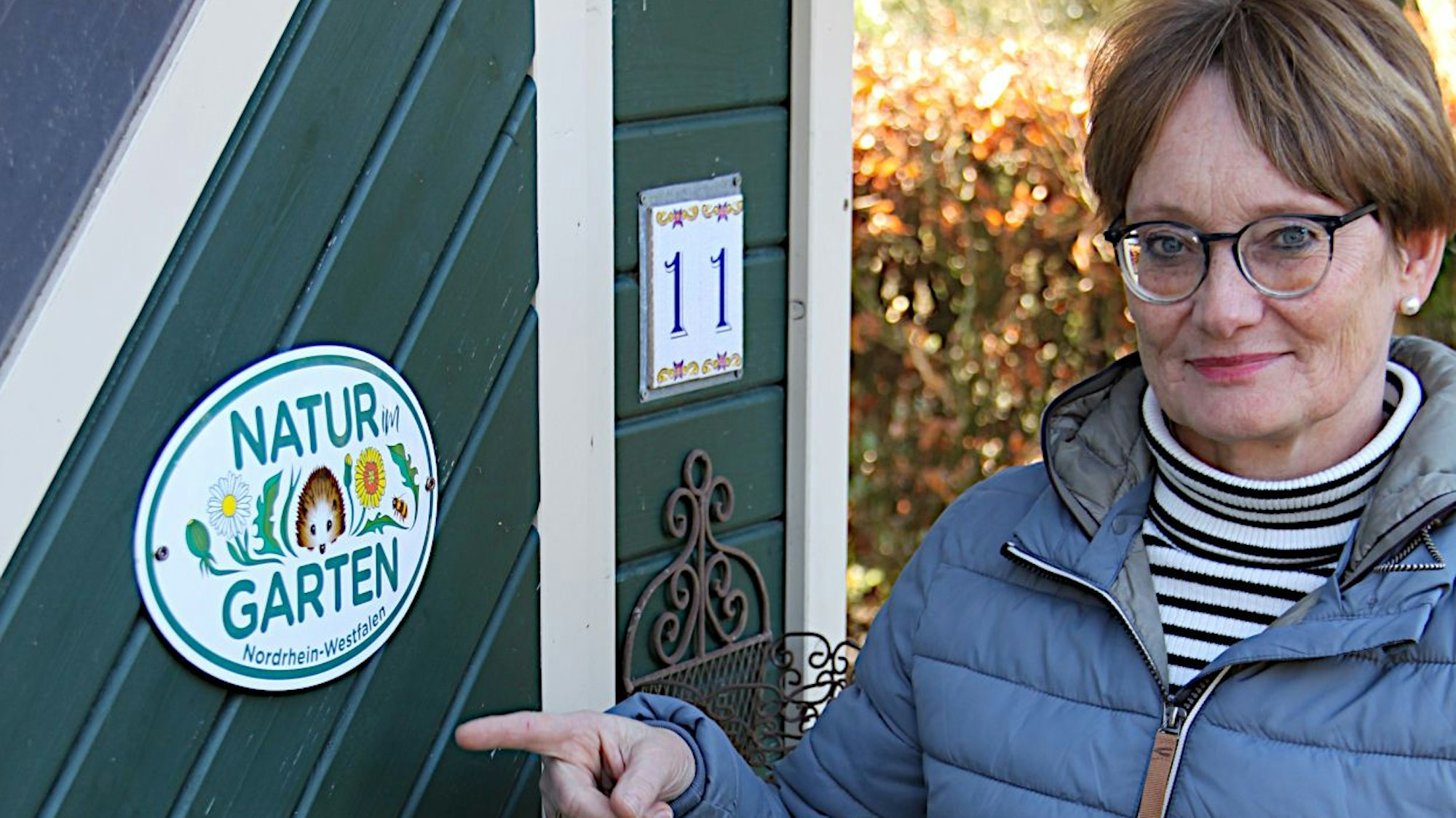 Simone Böhm deutet auf eine Plakette, die auf einer Holztür angebracht ist.