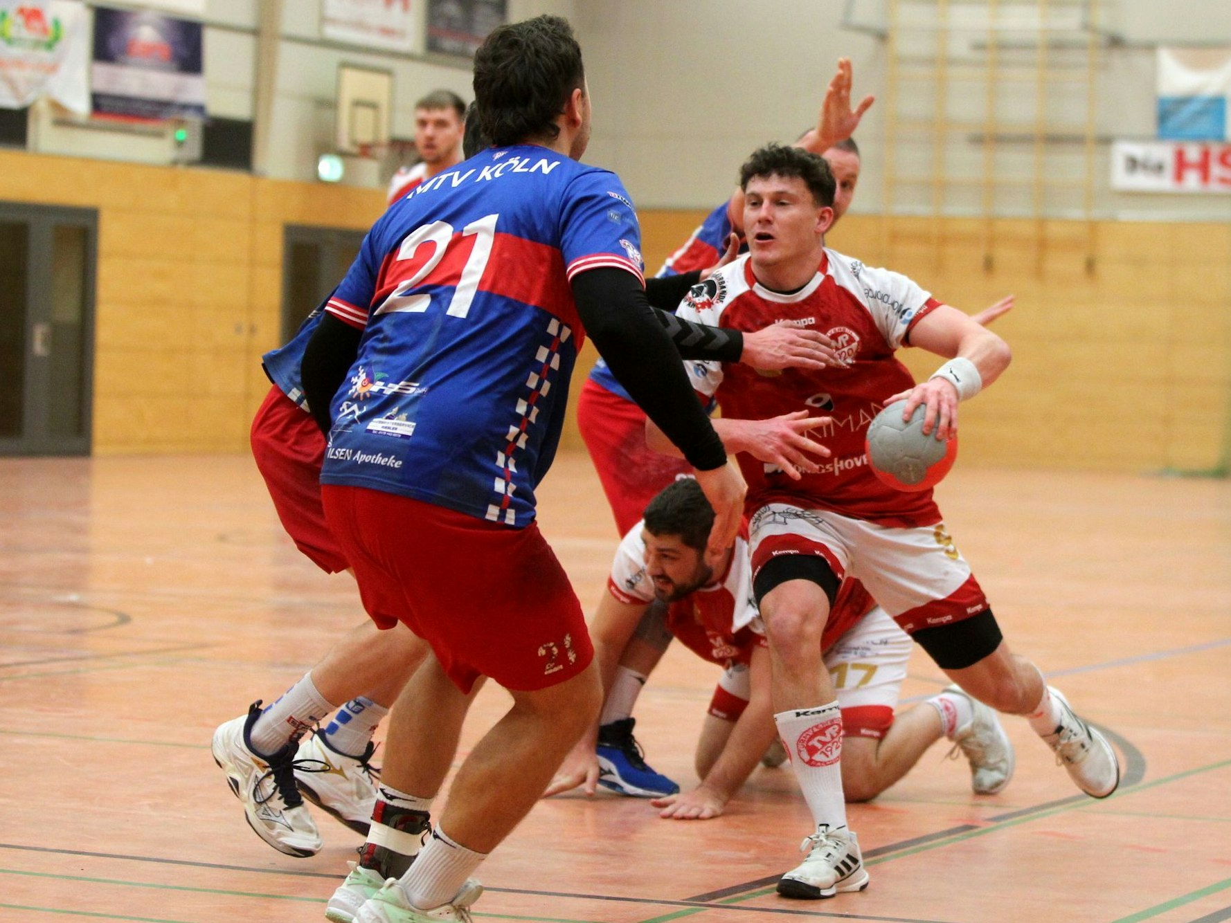 Marius Schmitz läuft mit dem Ball in der Hand in zwei gegnerische Verteidiger hinein. Im Hintergrund blockt ein zu Boden gegangener Palmersheimer einen weiteren Verteidiger.