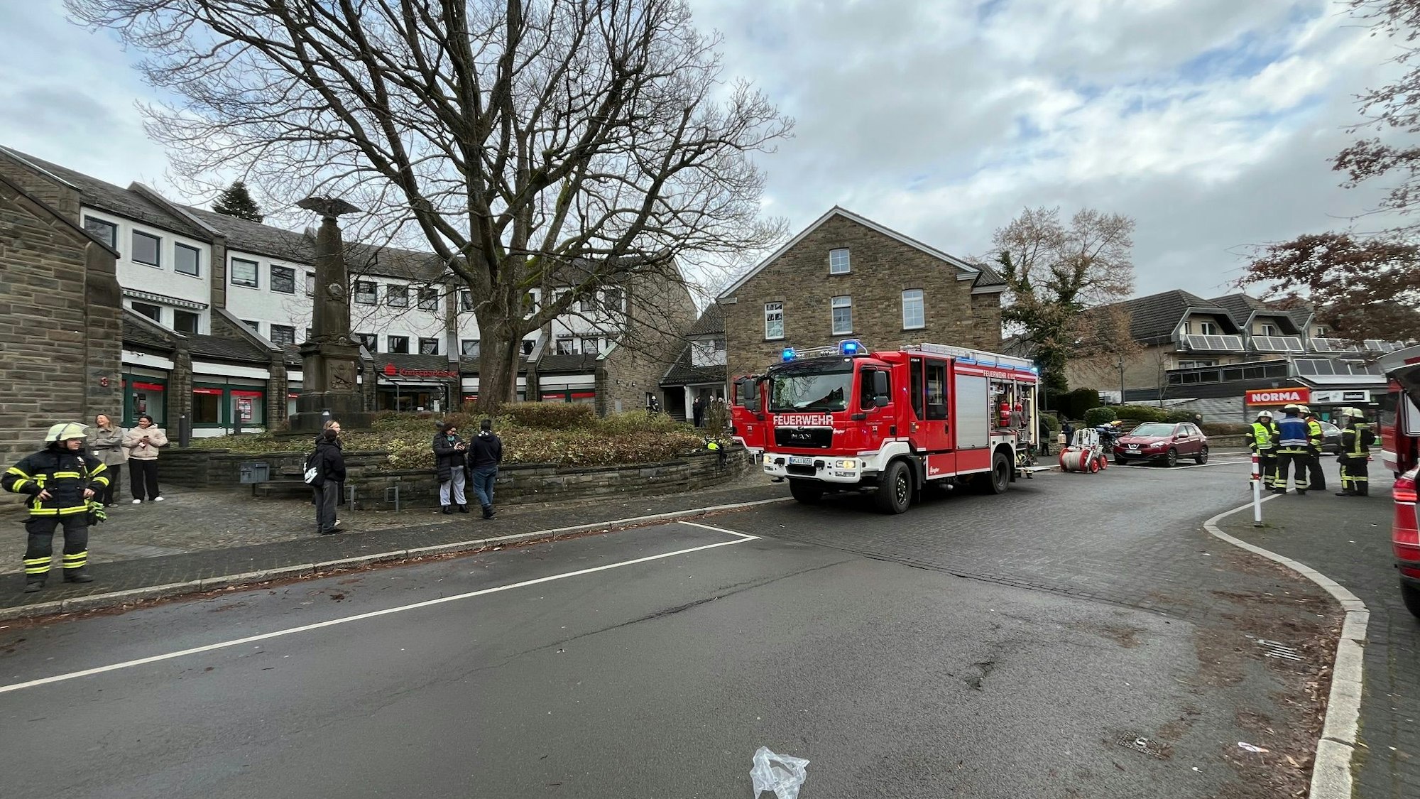 Das Foto zeigt ein Feuerwehrauto und Einsatzkräfte der Feuerwehr in Lindlar, vor der Geschäftsstelle der Kreissparkasse Köln