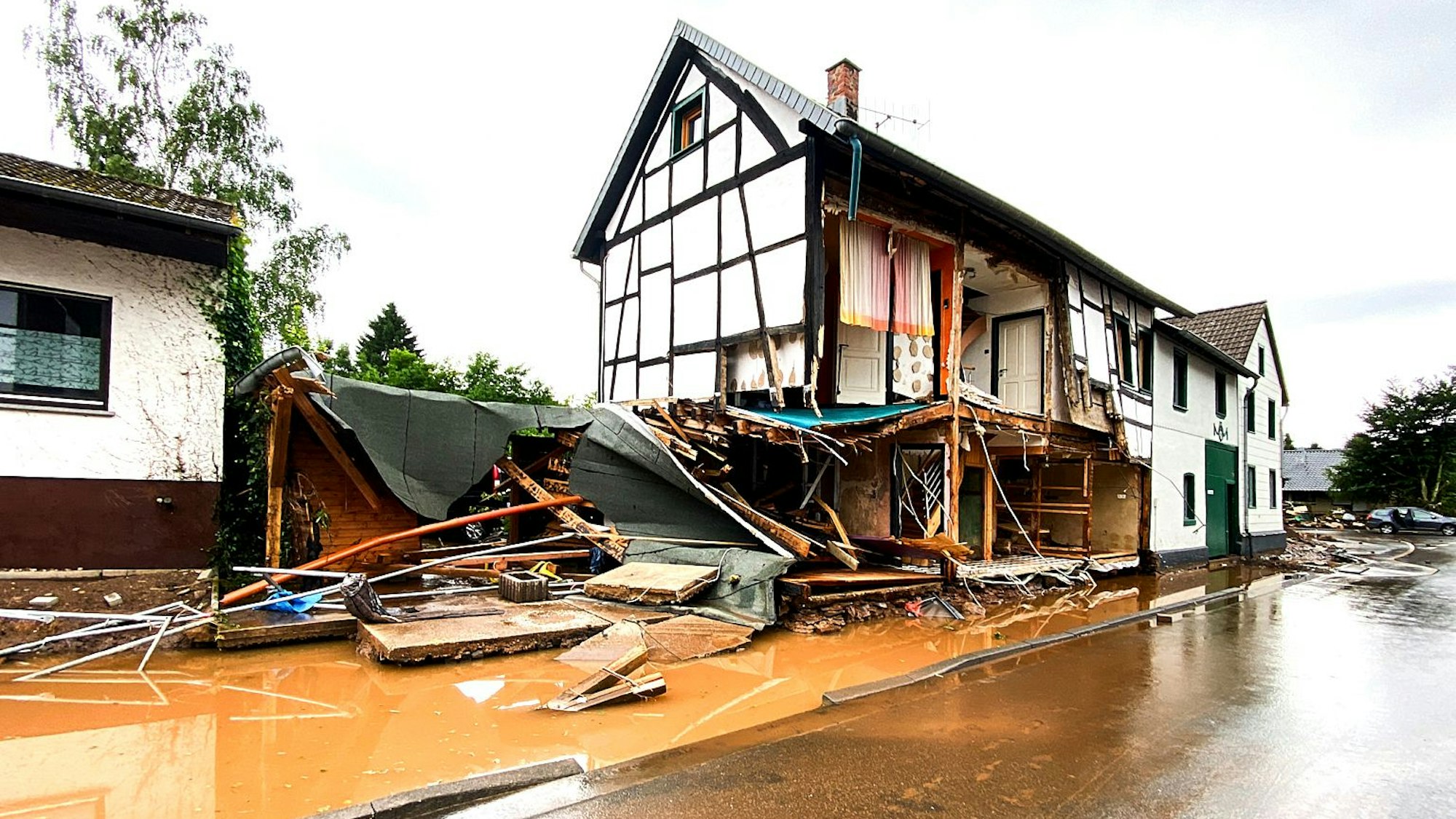 Ein Fachwerkhaus, dessen Untergeschoss komplett zerstört ist, ist zu sehen. Die Wassermassen hatten die Wände eingerissen.