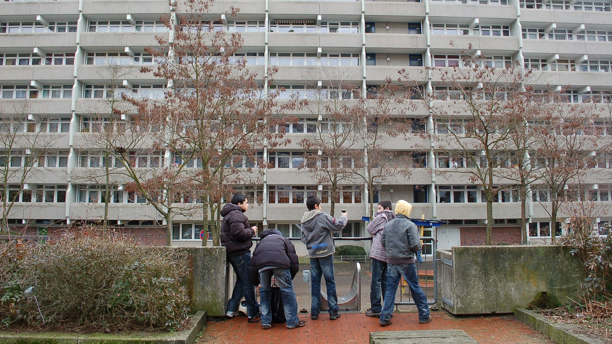 Kinder stehen vor einer Hochhauskulisse in Chorweiler.