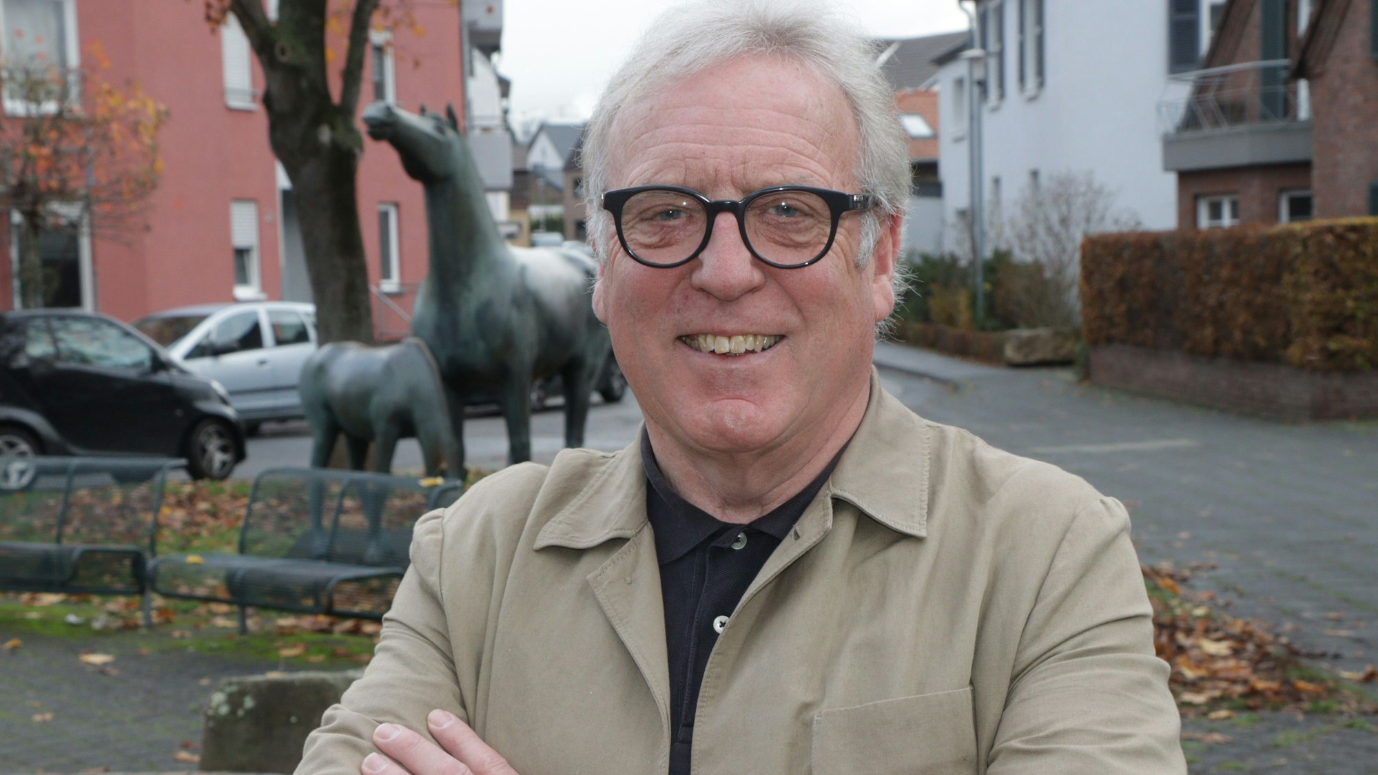 Ein Mann mit weißen Haaren und einer Brille mit schwarzem Gestell lächelt in die Kamera.