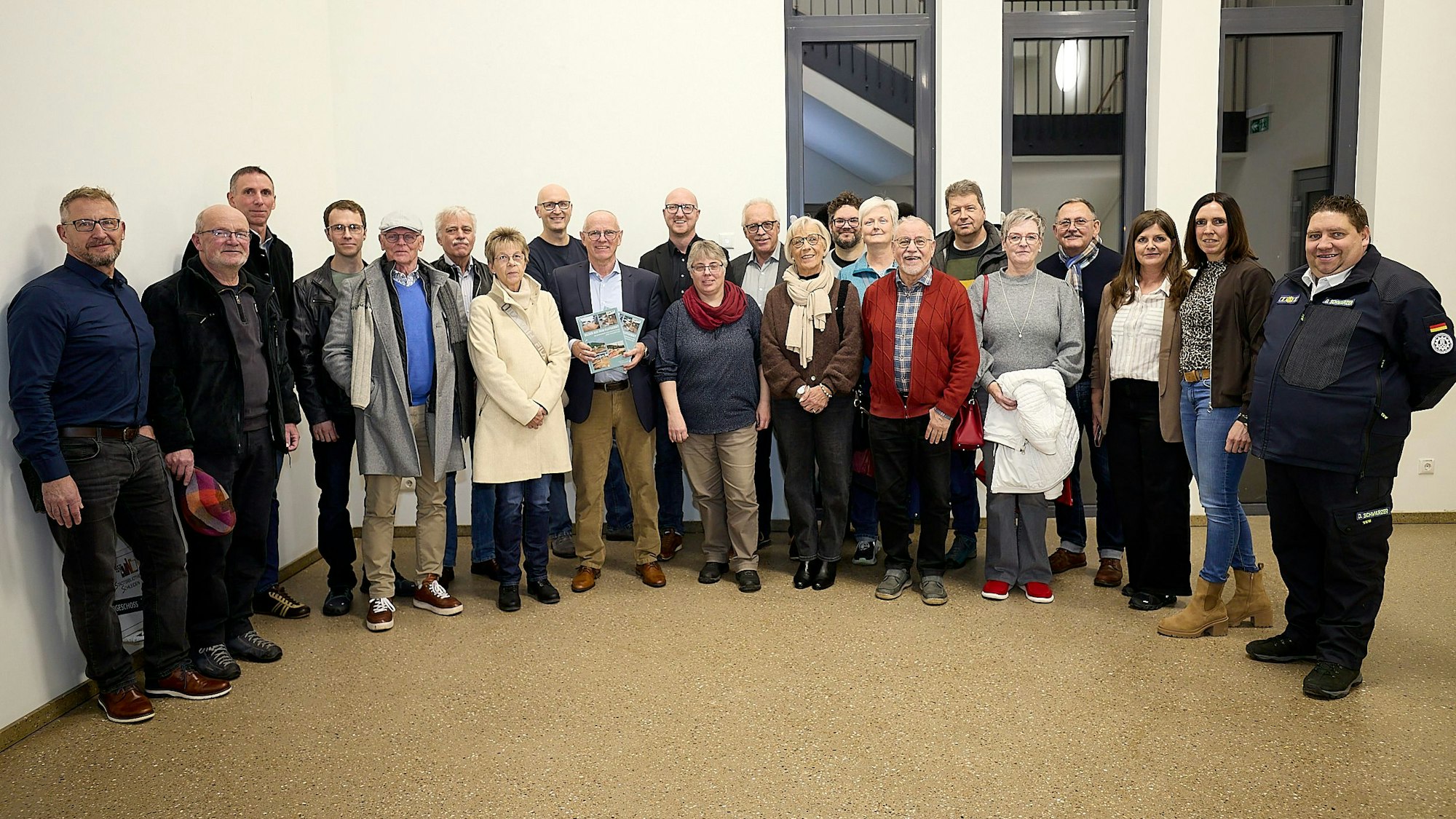 Eine Gruppe von Menschen steht nebeneinander, einer hält den BIldband in die Kamera.