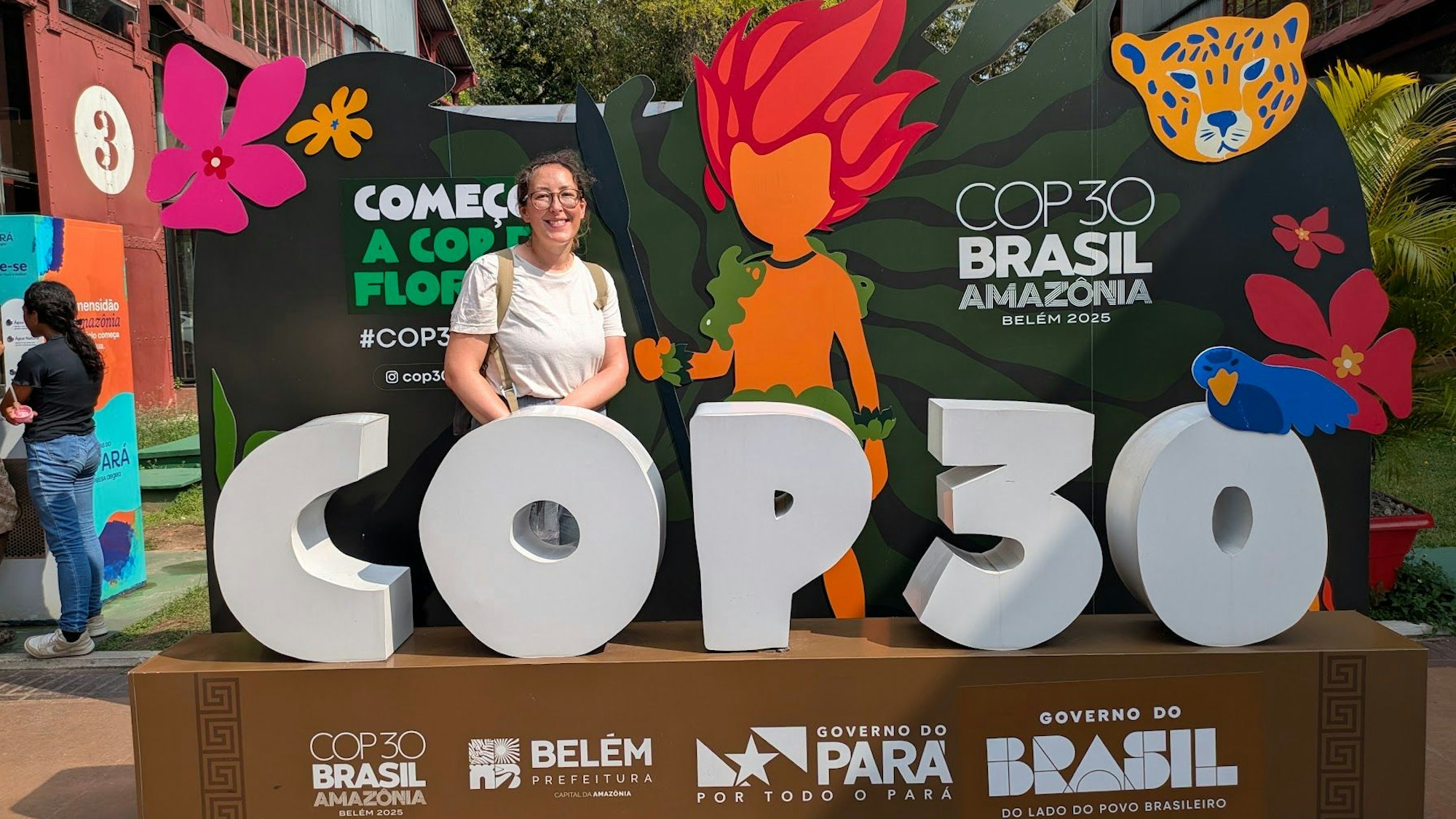 Eine Frau zwischen den Logos der Weltklimakonferenz.