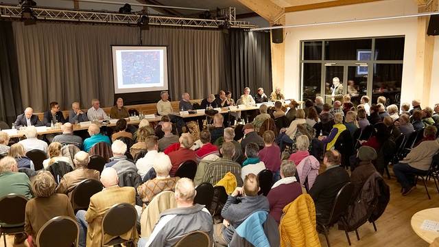 Das Bild zeigt die besetzten Stuhlreihen und das Podium.