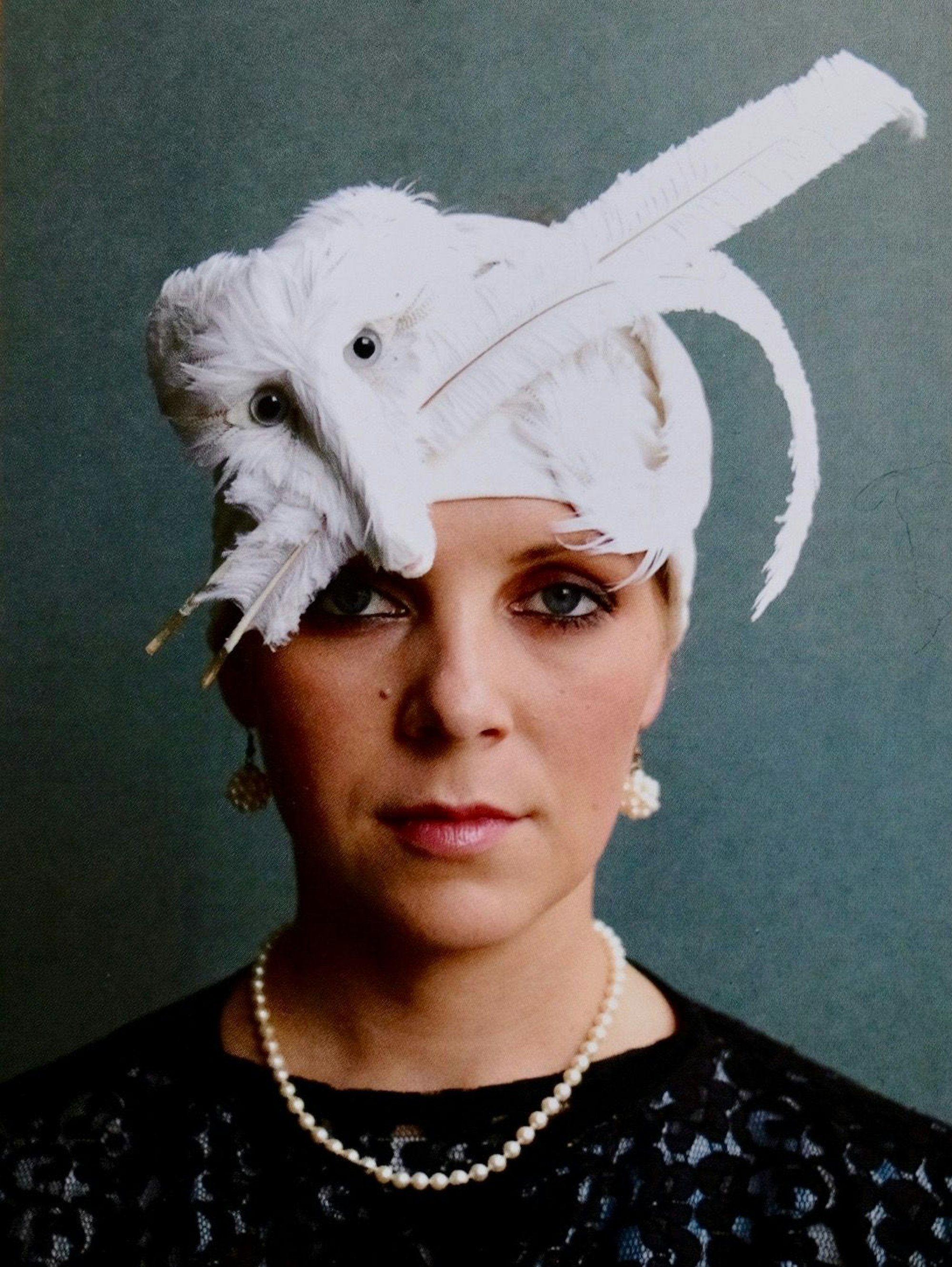 Eine Frau trägt eine Kappe aus Gänsefedern, die einen Polarfuchs darstellt.