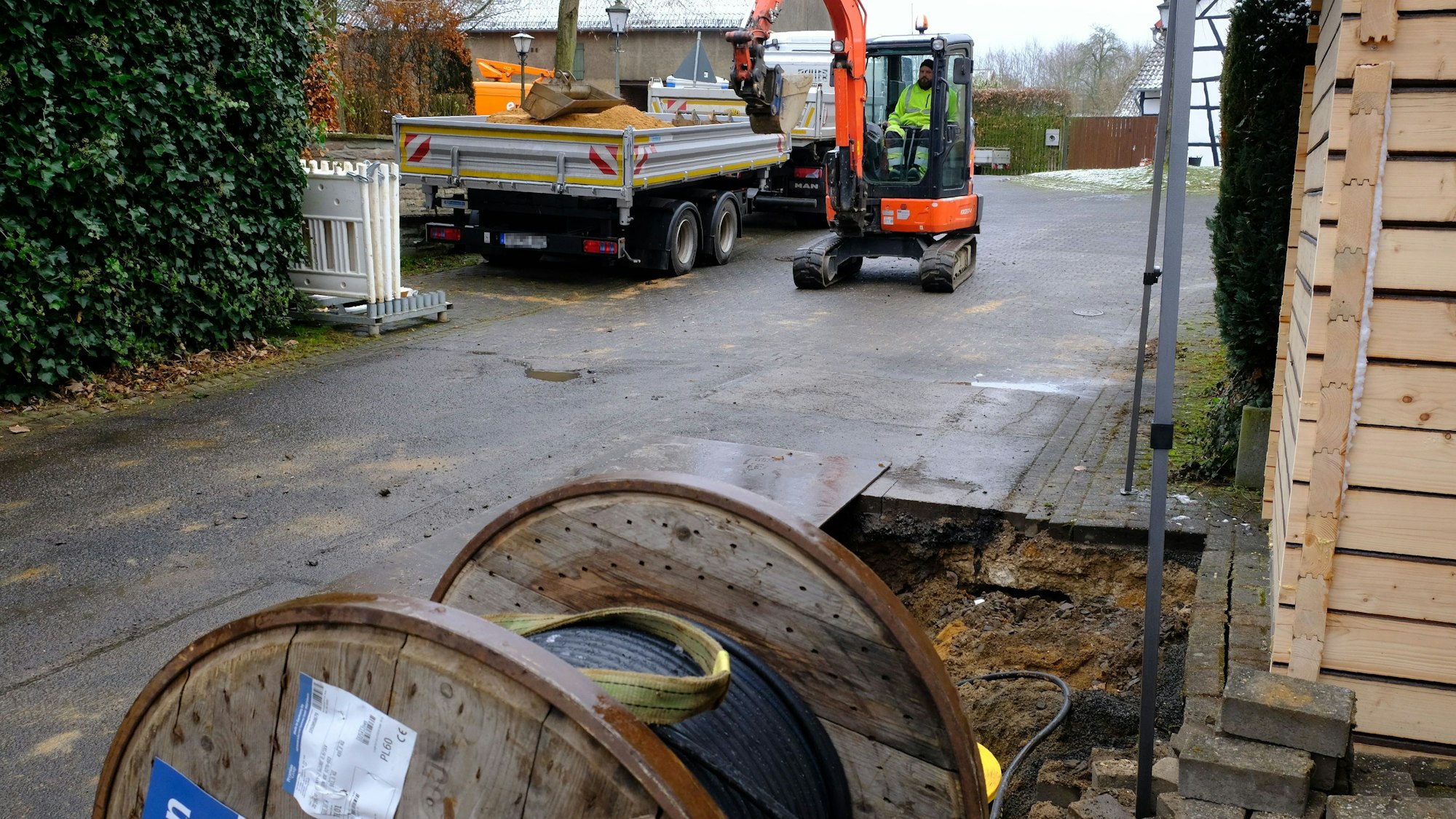 Baustelle in Buir: Vor der aufgerissenen Straße liegt eine Kabeltrommel, im Hintergrund sind Baumaschinen zu sehen.