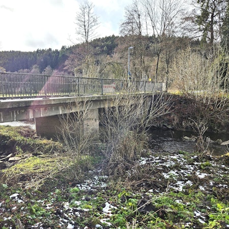 Blick von der Seite auf die alte Brücke, die bei Anstois über die Urft führt.