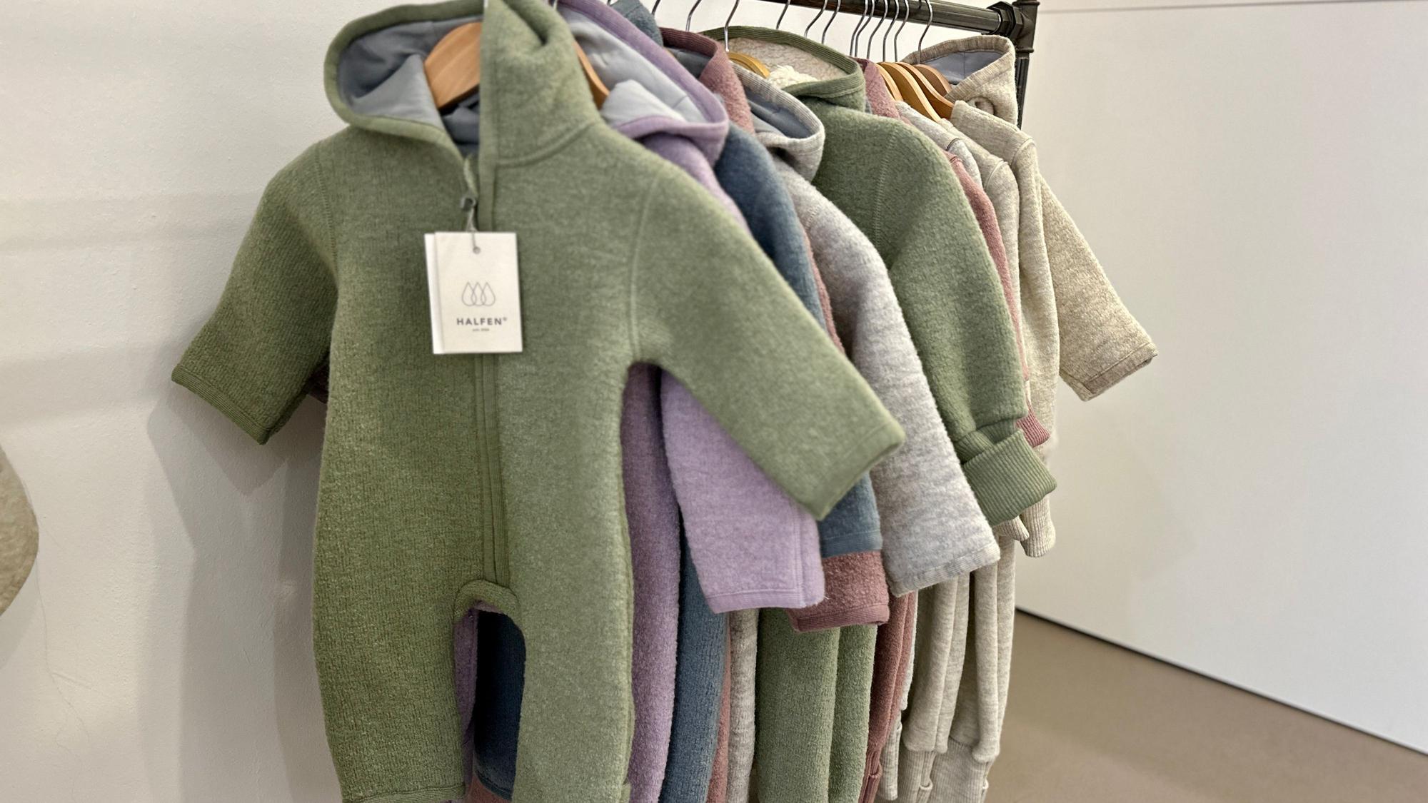 An einem Ständer hängen Woll-Overalls in verschiedenen Farben.
