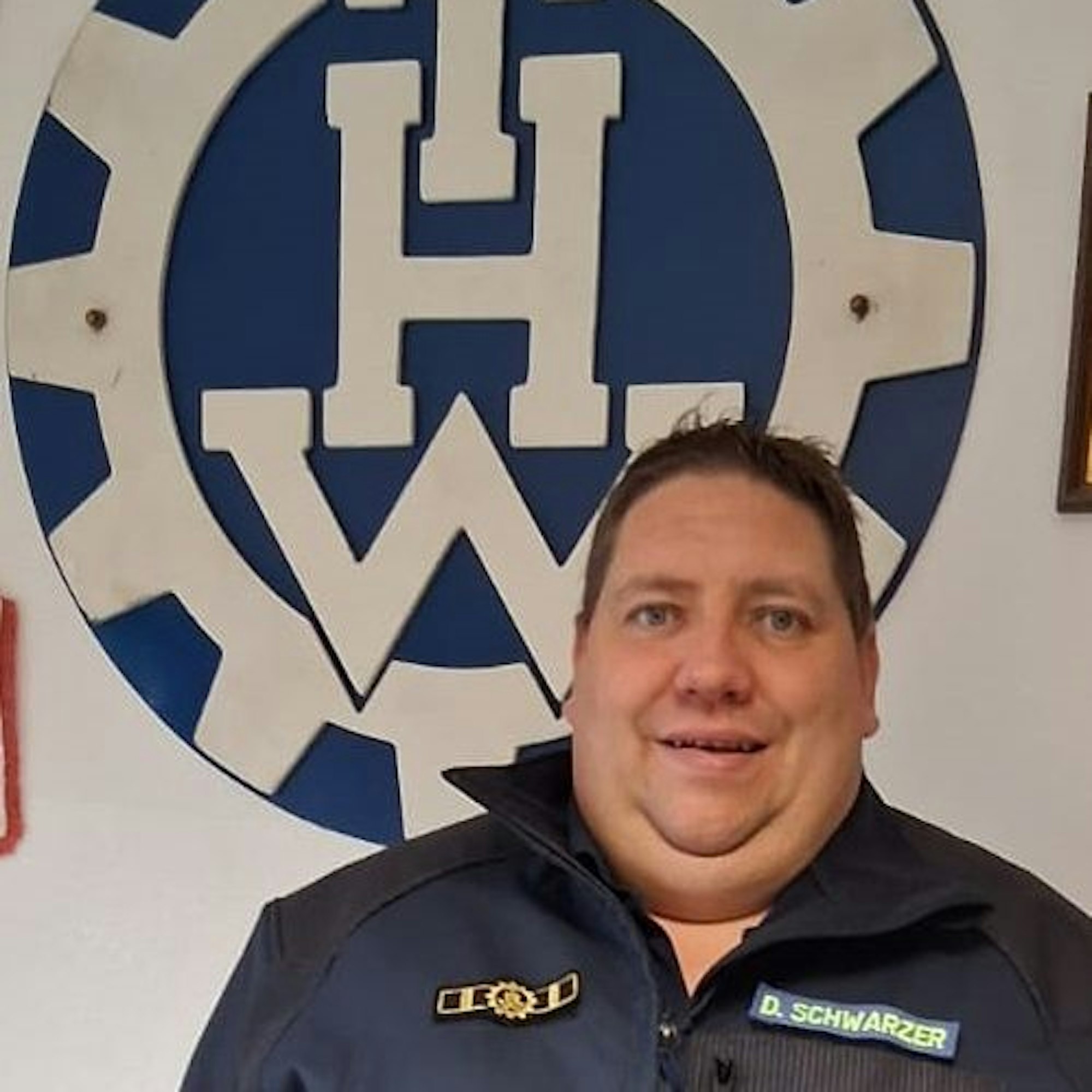 Daniel Schwarzer steht vor einem THW-Schild.