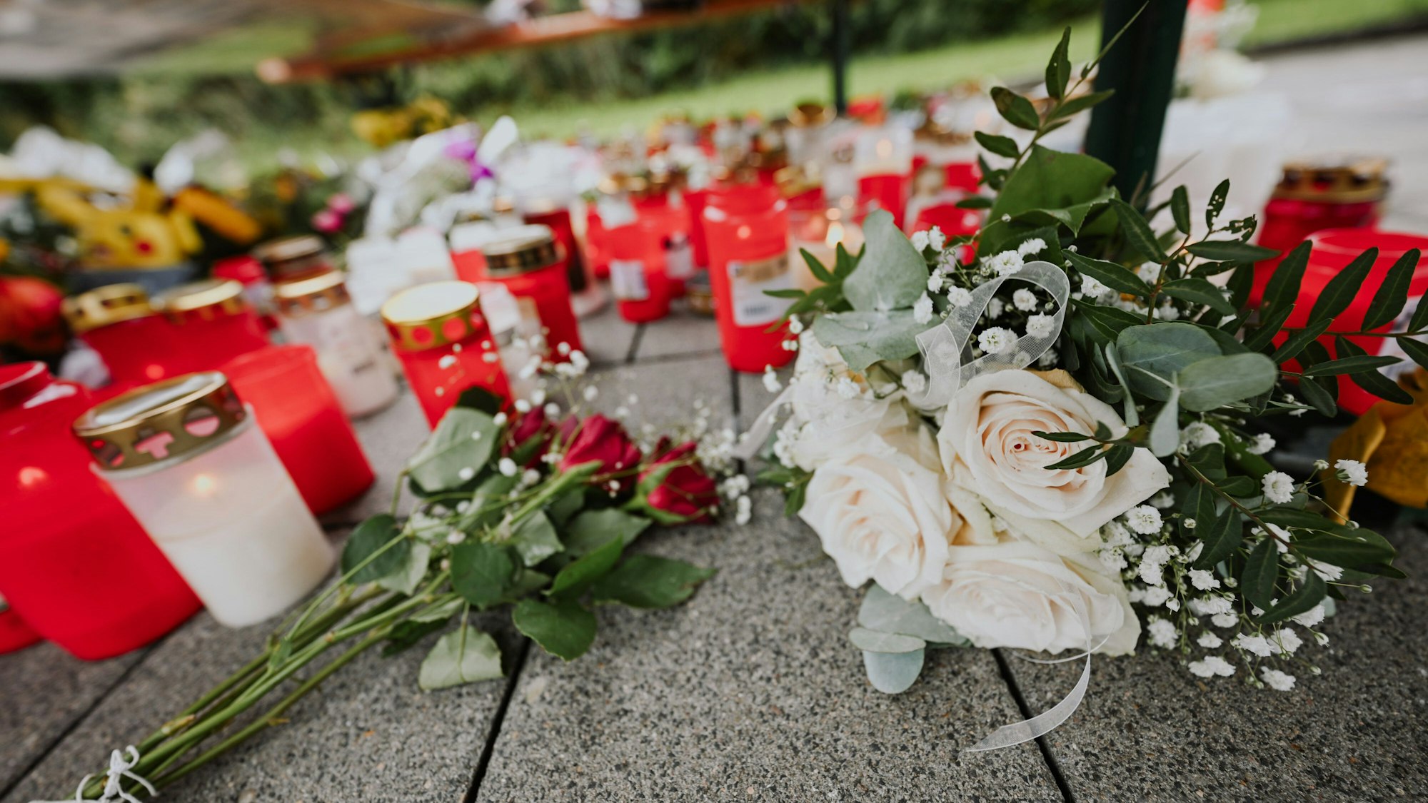 Blumen und Kerzen liegen zum Gedenken auf dem Boden (Symbolfoto).