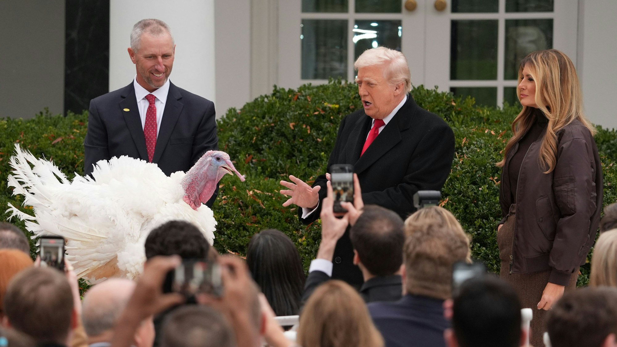 Das Bild zeigt US-Präsident Donald Trump (M) und First Lady Melania Trump (r) neben dem nationalen Thanksgiving-Truthahn während einer Begnadigungszeremonie im Rosengarten des Weißen Hauses. Foto: Evan Vucci/AP/dpa