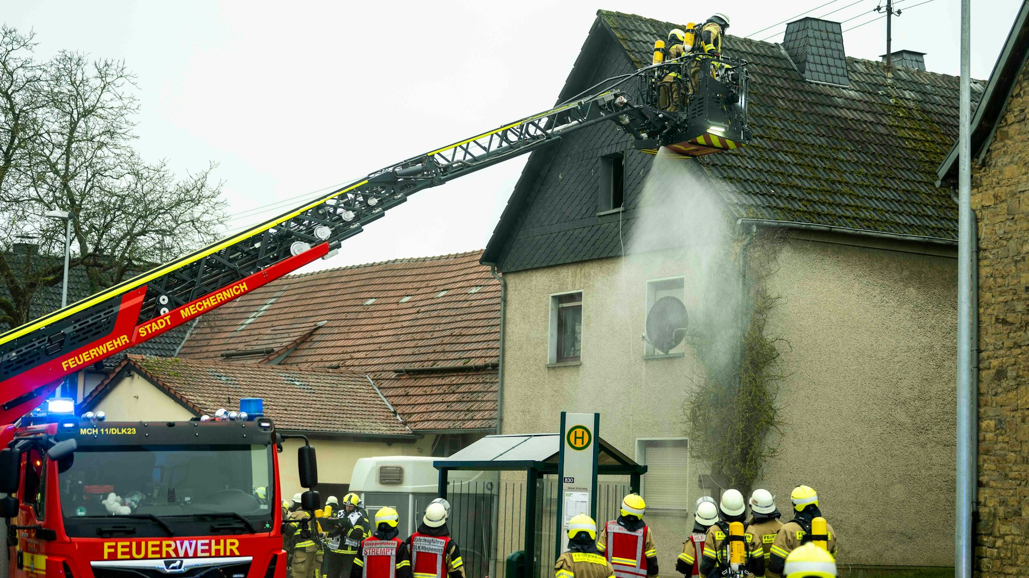 Vom Korb einer Drehleiter aus kühlen Feuerwehrleute mit einem Strahlrohr die Fassade desb Gebäudes.