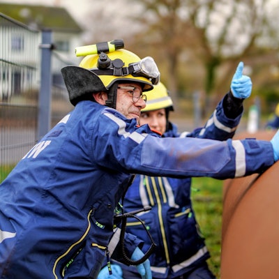 Zwei THW-Mitglieder hantieren an einem großen Stahlrohr.
