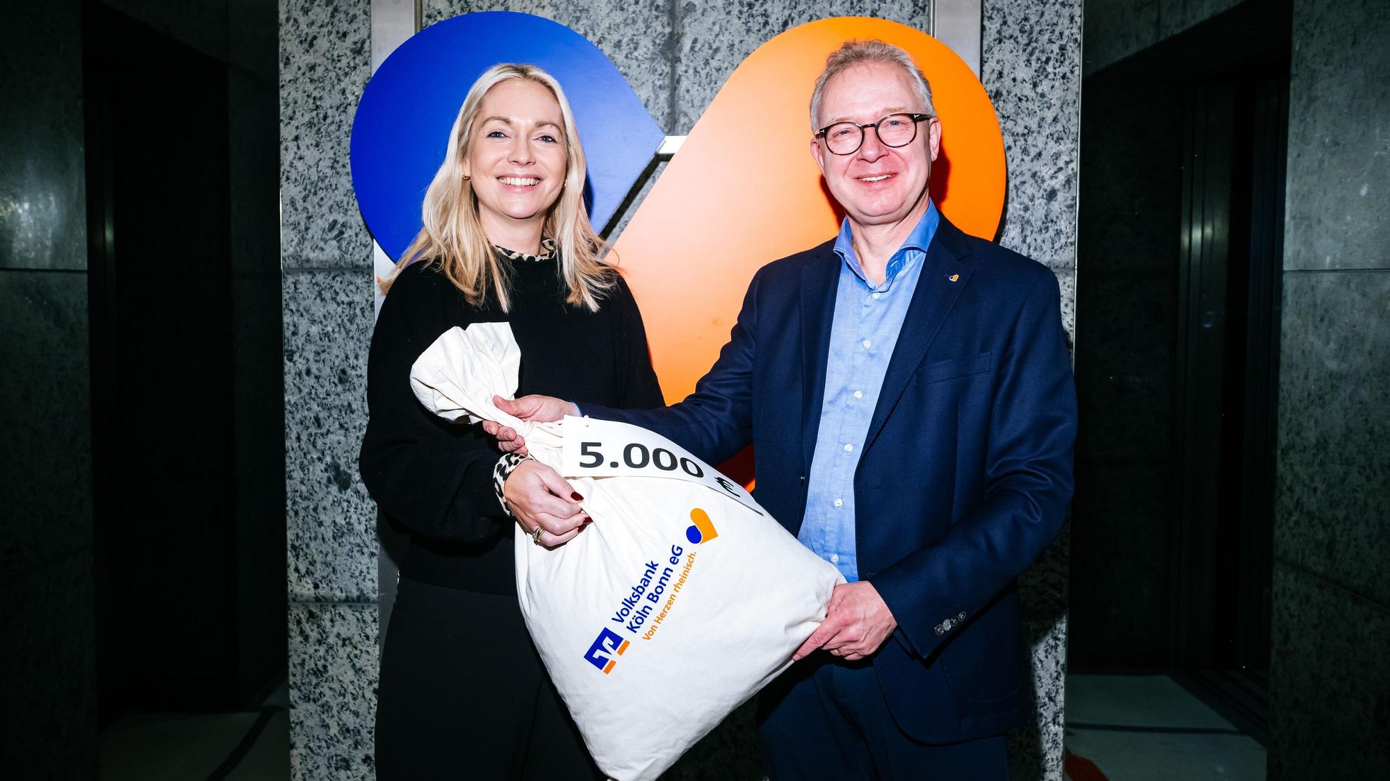 Einen Sack voll Geld - zumindest symbolisch - überreicht Jürgen Pütz, Vorstandsvorsitzender der Volksbank, der Altenhilfe-Vorsitzenden Julia Heinen.