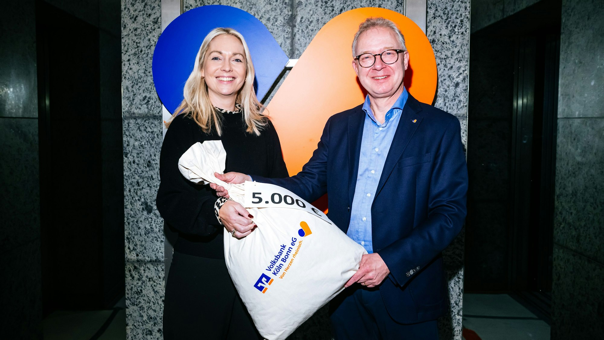 Einen Sack voll Geld - zumindest symbolisch - überreicht Jürgen Pütz, Vorstandsvorsitzender der Volksbank, der Altenhilfe-Vorsitzenden Julia Heinen.