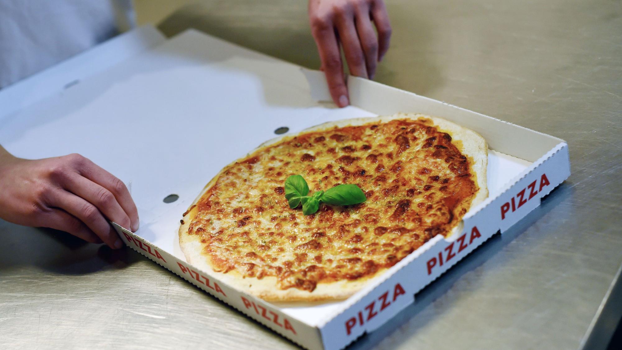 Zu sehen ist eine Pizza im Karton.