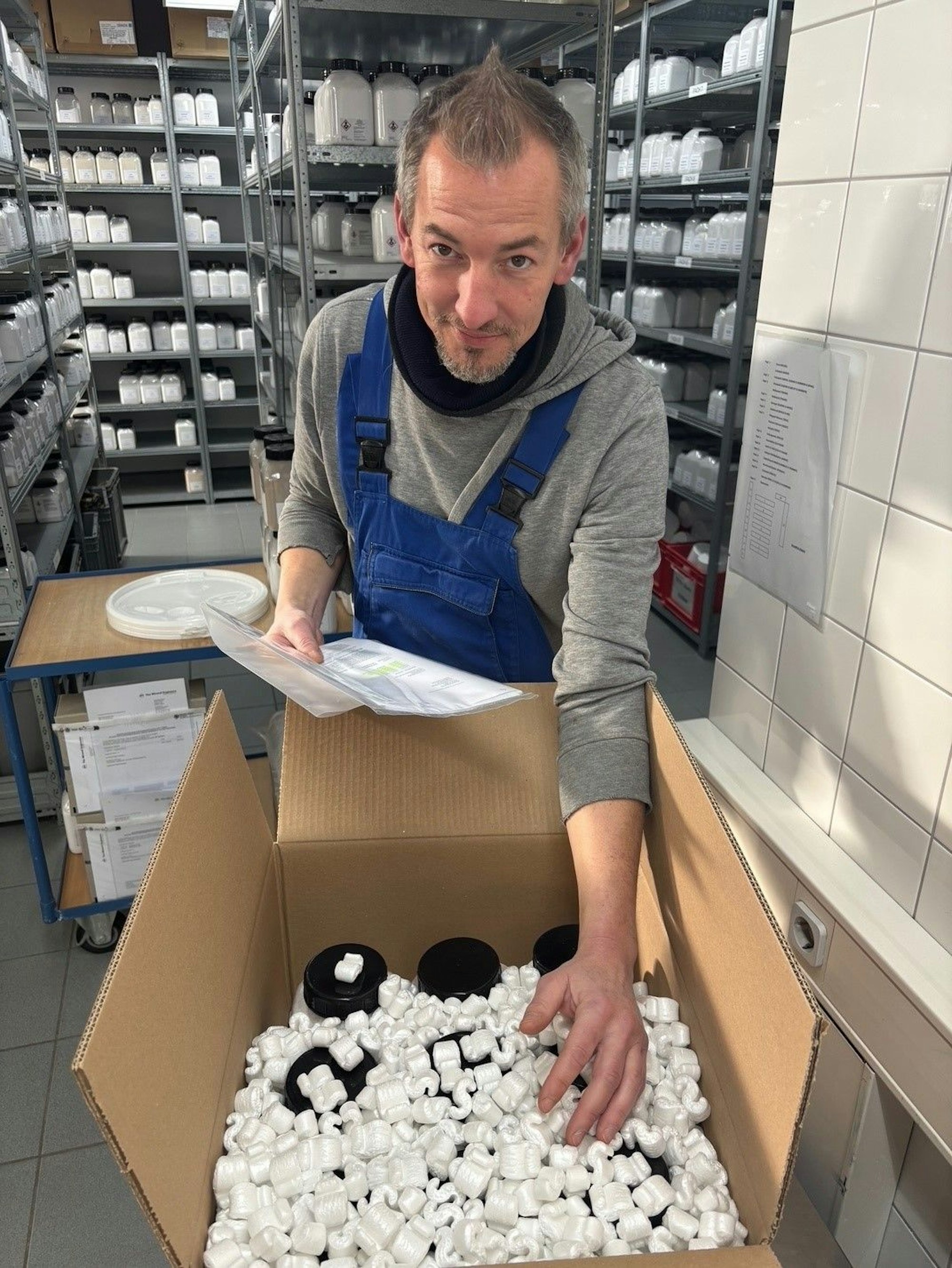 Auf dem Bild ist ein Mann zu sehen, der die Produktproben in einen Karton packt.