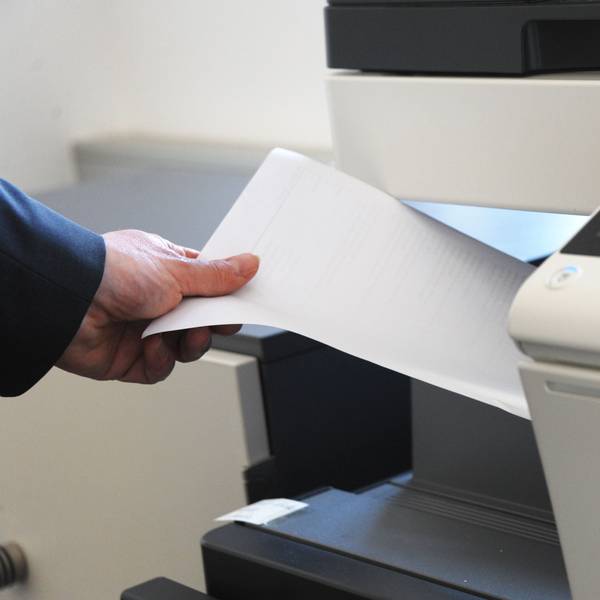 Eine Person holt Papier aus einem Kopierdrucker.