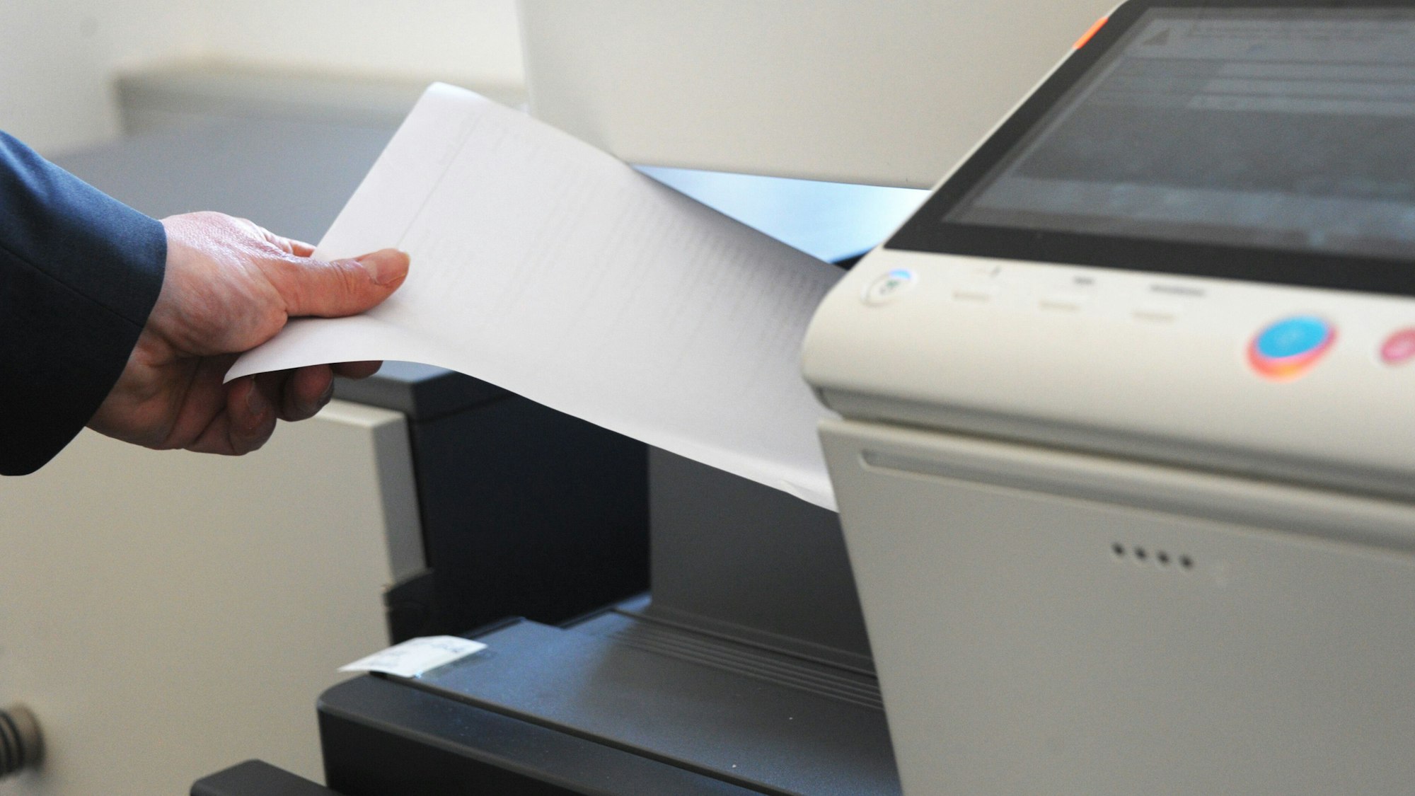Eine Person holt Papier aus einem Kopierdrucker.
