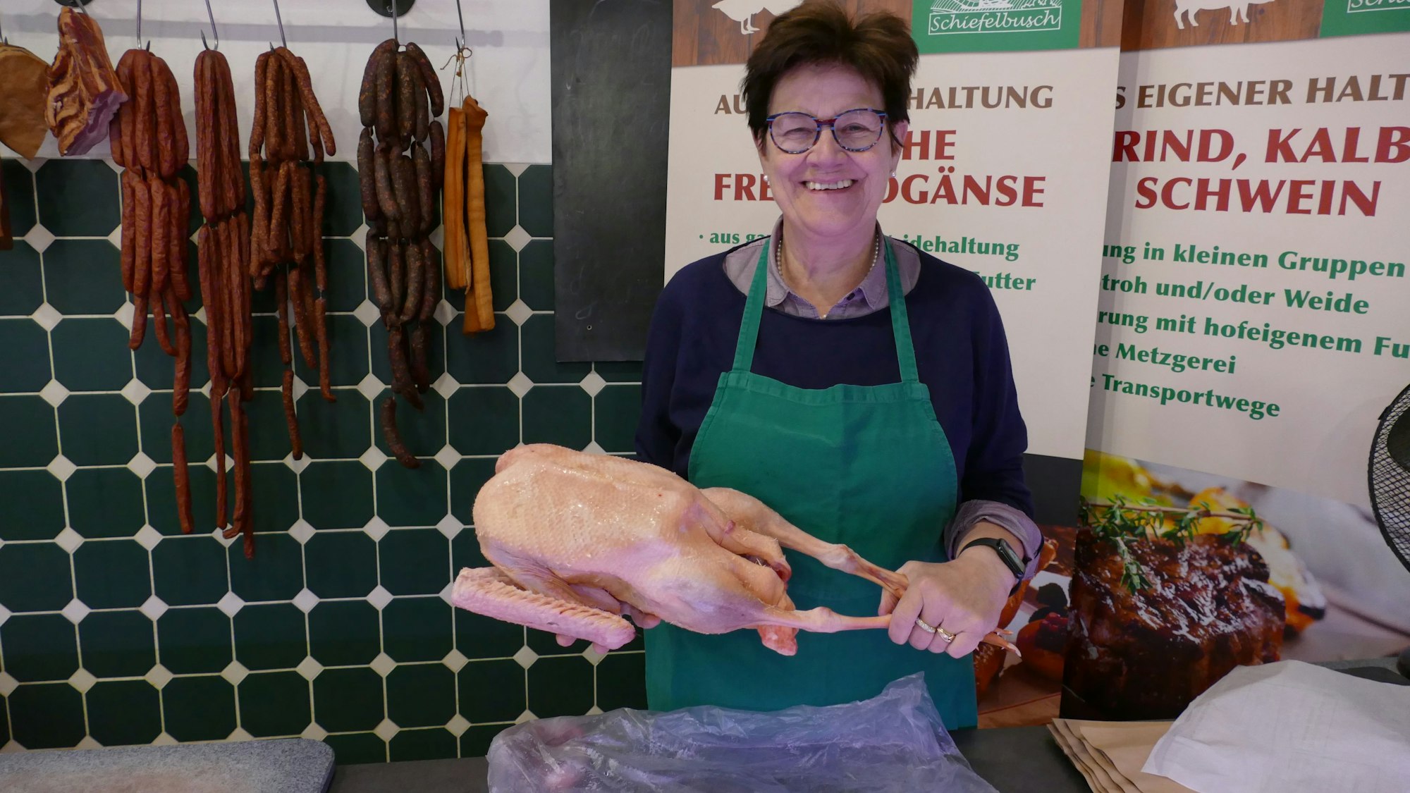 Helga Trimborn mit Geflügel in der Hand in ihrem Hofladen.