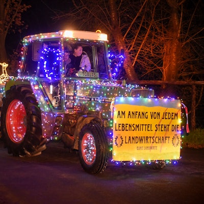 Ein mit bunten Lichterketten geschmückter Traktor.