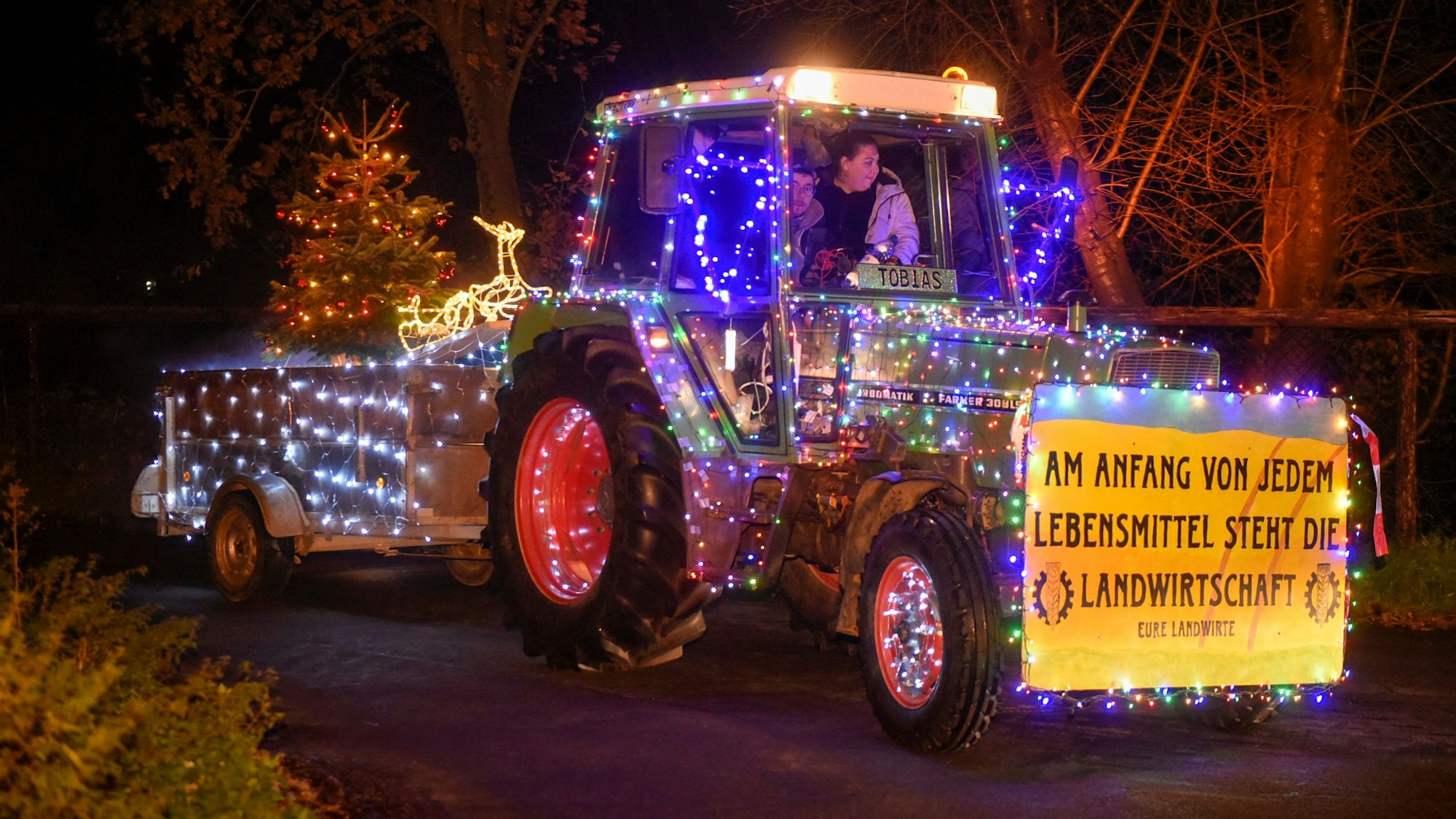 Ein mit bunten Lichterketten geschmückter Traktor.