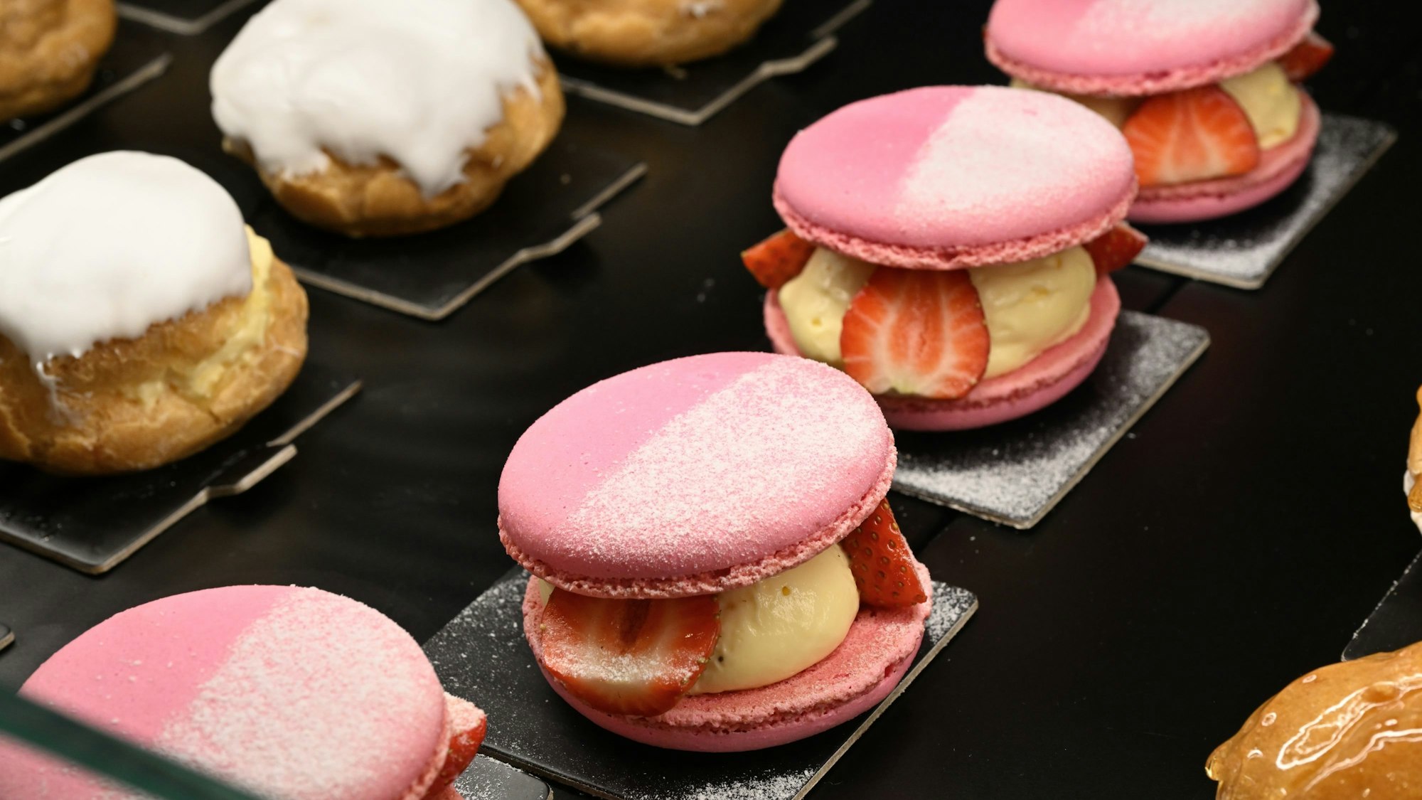 In einer Auslage liegen rosafarbene Macarons.