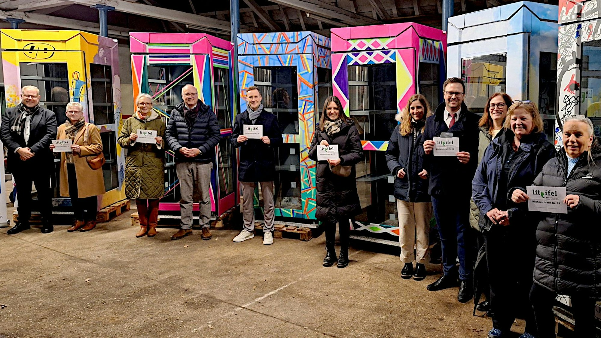 Vor den bunt bemalten ehemaligen Telefonzellen stehen die Bürgermeisterinnen und Bürgermeister, die sie zur Leseförderung angeschafft haben.