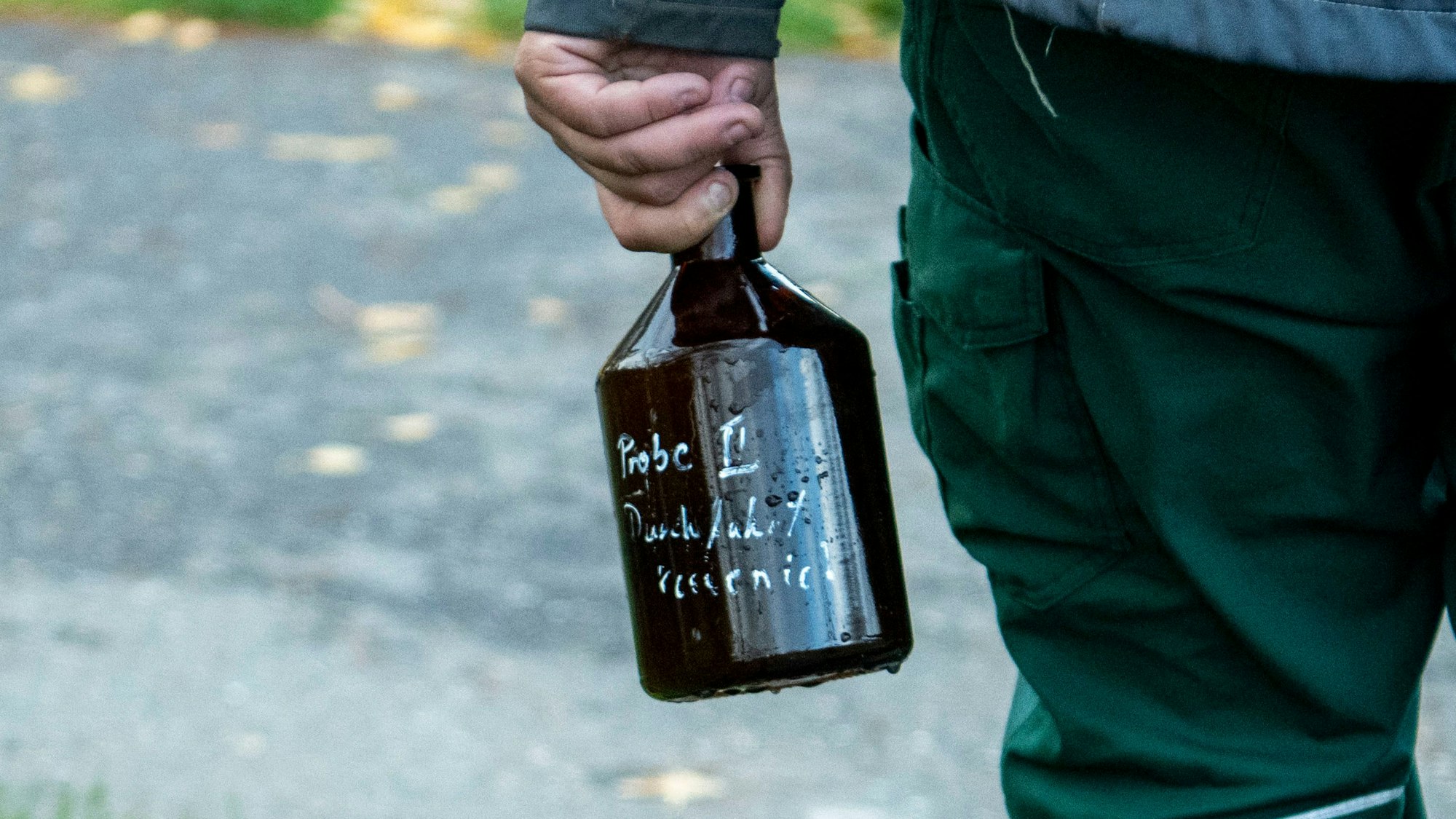 Das Bild zeigt einen Mitarbeiter des Erftverbands, der eine Falsche mit einer Wasserprobe trägt.