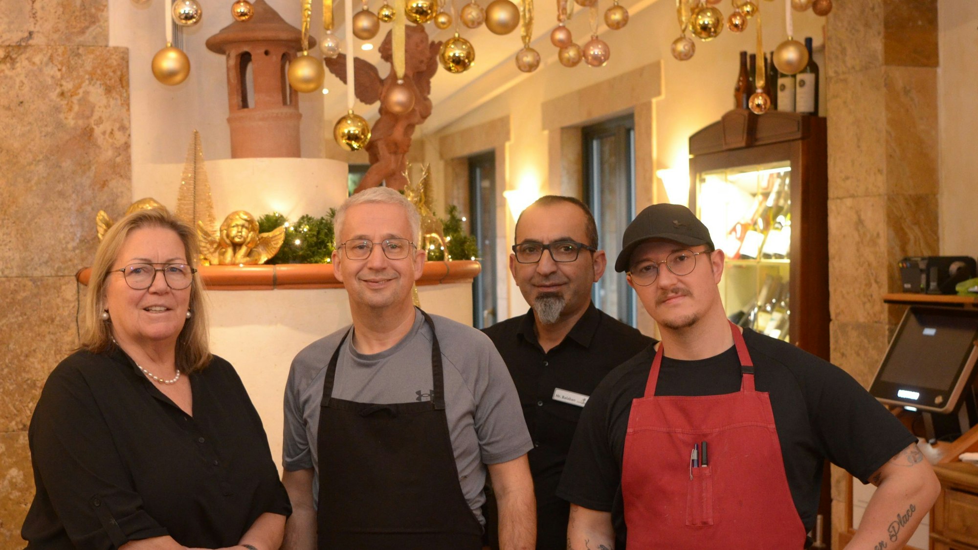 Das Quartett steht vor einem Kamin, an der Decke hängen Weihnachtskugeln.