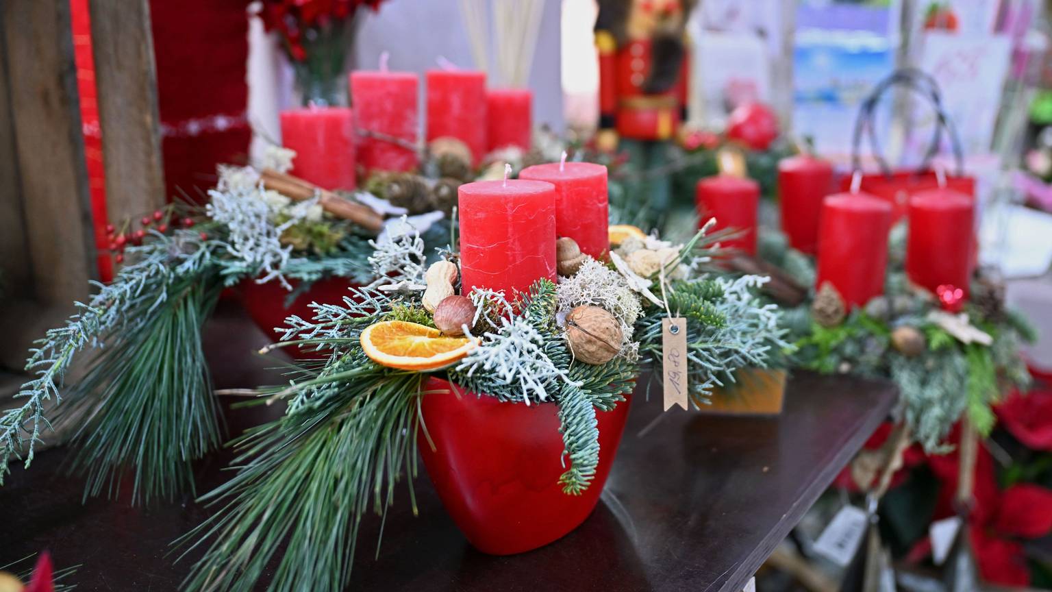 Mehrere weihnachtlich dekorierte Adventskränze mit roten Kerzen stehen in einem Blumenladen (Symbolbild)