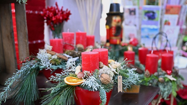 Mehrere weihnachtlich dekorierte Adventskränze mit roten Kerzen stehen in einem Blumenladen (Symbolbild)