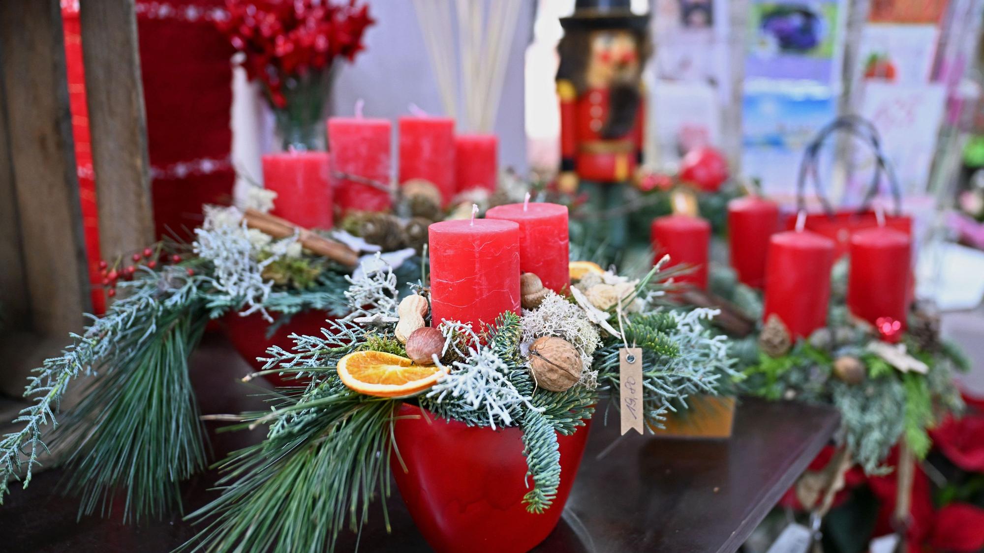 Mehrere weihnachtlich dekorierte Adventskränze mit roten Kerzen stehen in einem Blumenladen (Symbolbild)
