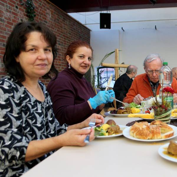 Das Foto zeigt Menschen, die gemeinsam an einem Tisch sitzen und essen.