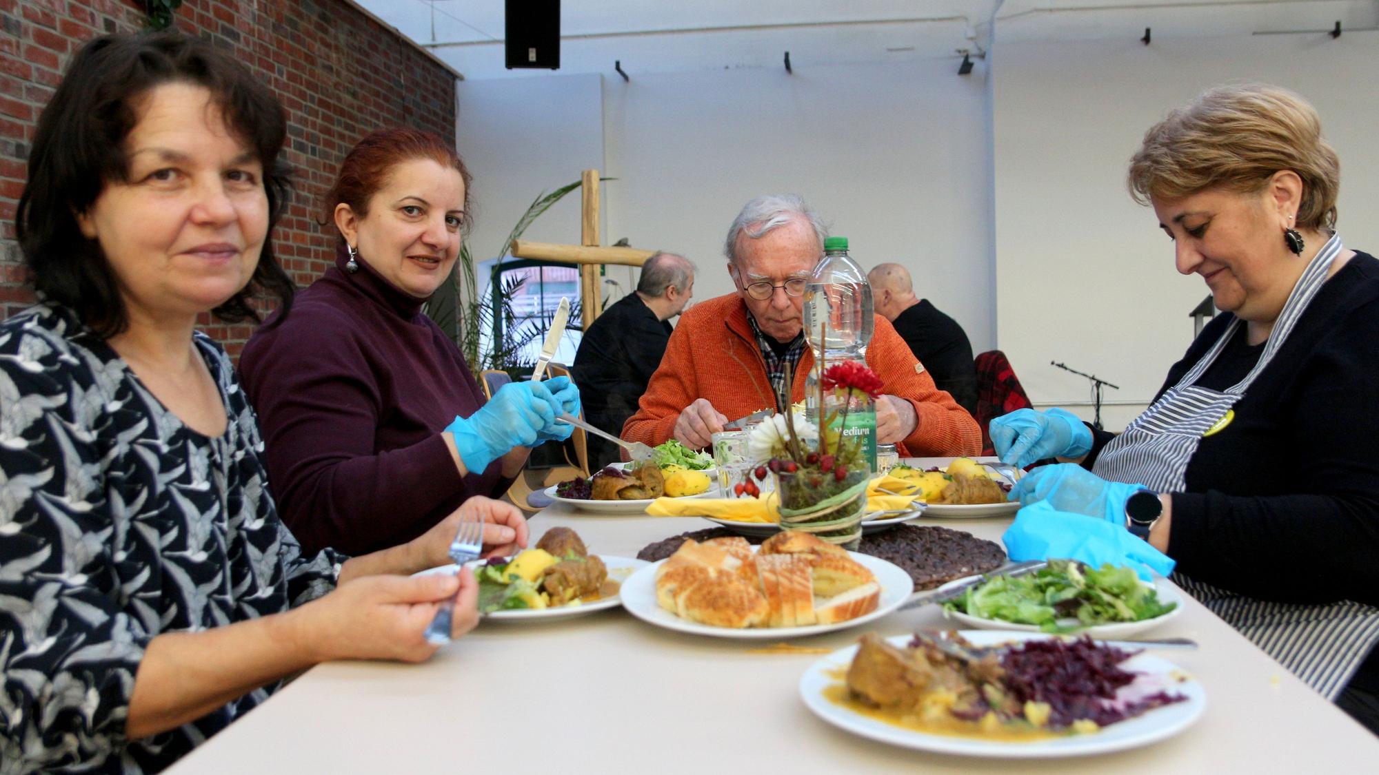 Das Foto zeigt Menschen, die gemeinsam an einem Tisch sitzen und essen.