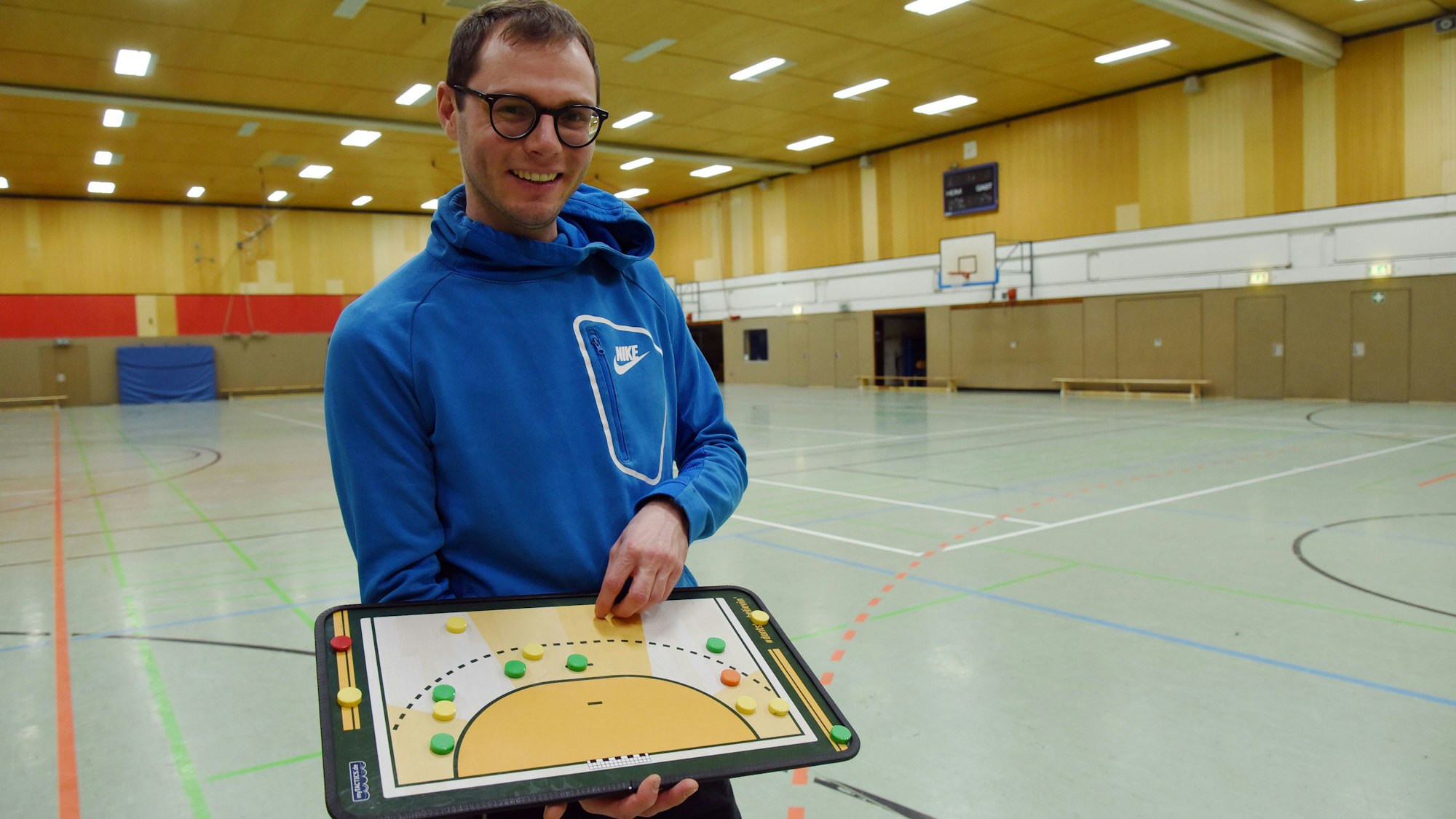 Handballtrainer David Hoffmann hält eine Spielfeld-Magnettafel in den Händen.