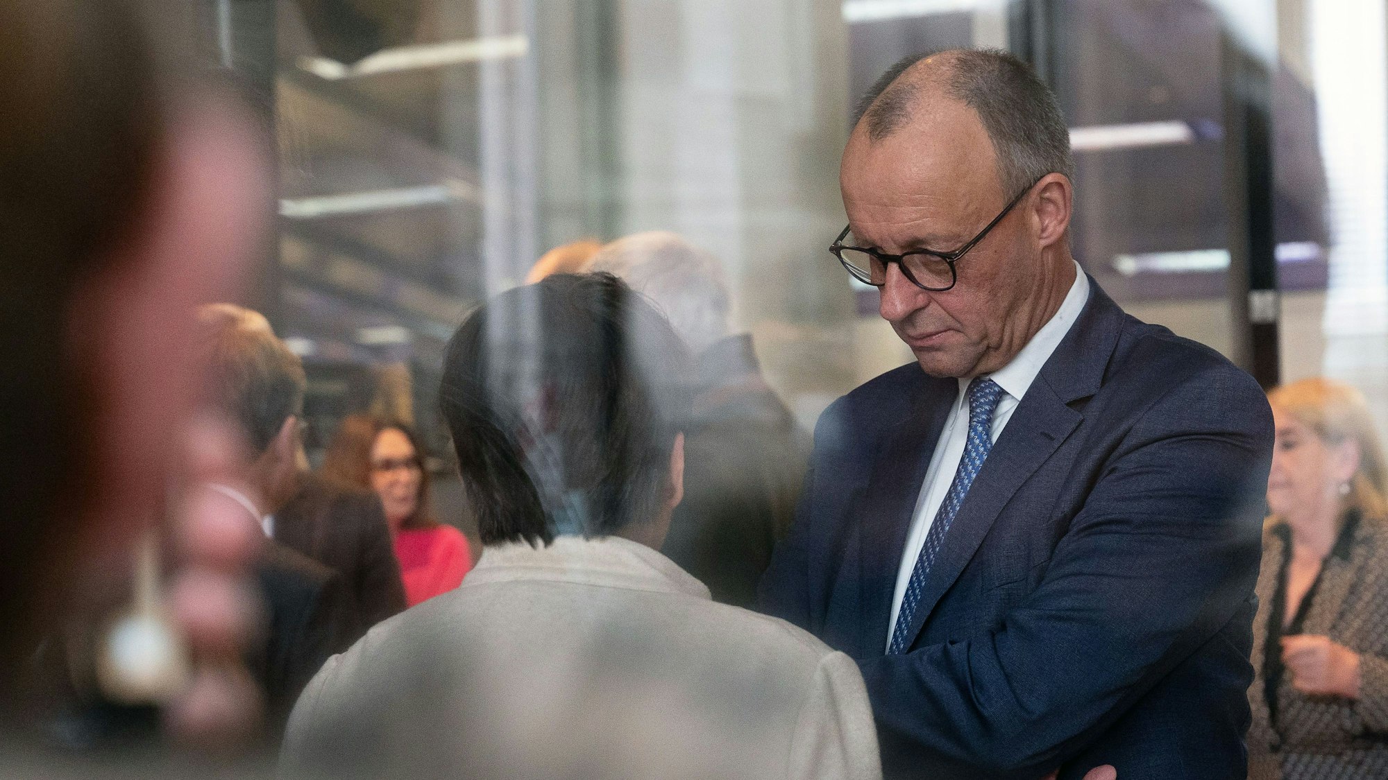 Bundeskanzler Friedrich Merz (r, CDU) im Gespräch mit Bundestagsabgeordneten bei einer namentlichen Abstimmung im Bundestag.