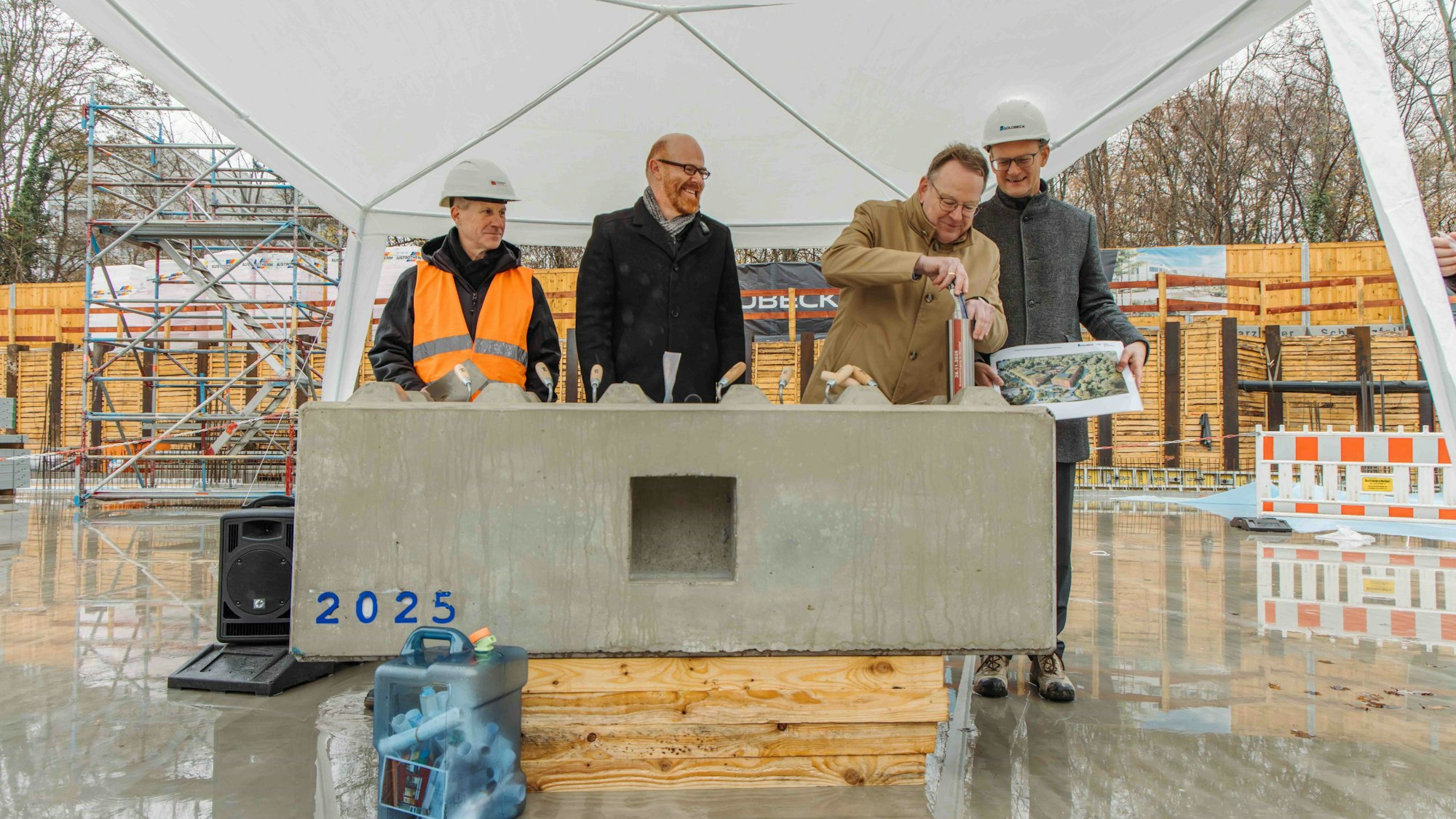Vier Männer haben sich um einen Grundstein aus Beton versammelt.
