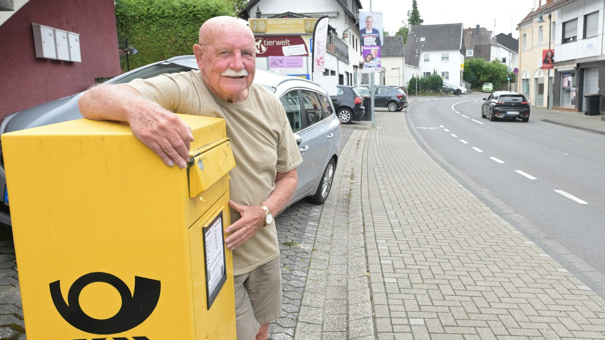 Rösrather Anwohner Malte Retiet umarmt einen Briefkasten der Deutschen Post.